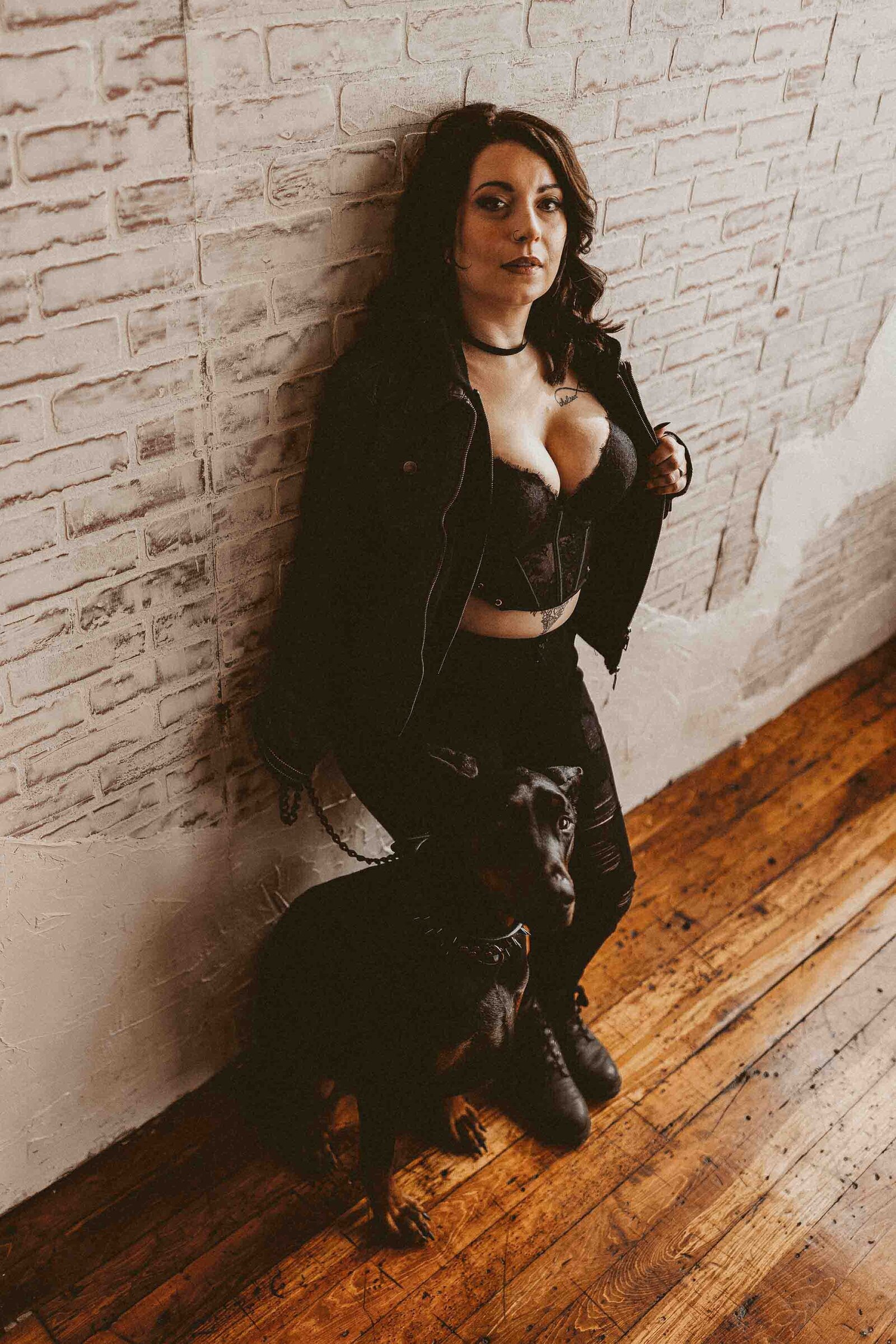 woman leaning on the wall with her dog beside her