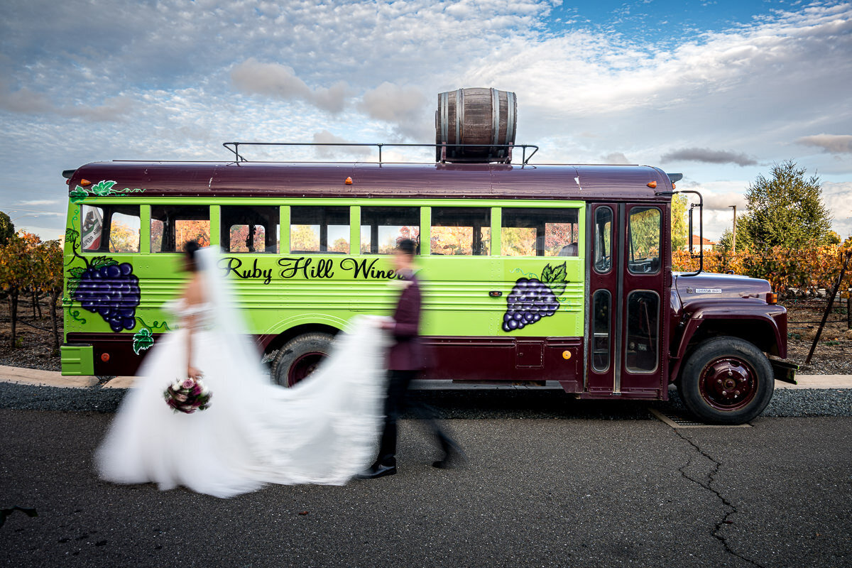 A romantic shot of the bride and groom walking hand in hand in front of a vintage bus at Casa Real Winery in Pleasanton, California. The couple is glowing with joy against the backdrop of the winery’s elegant charm, creating a timeless and picturesque moment on their wedding day. Perfectly capturing the essence of love and sophistication at this iconic Northern California wedding venue.