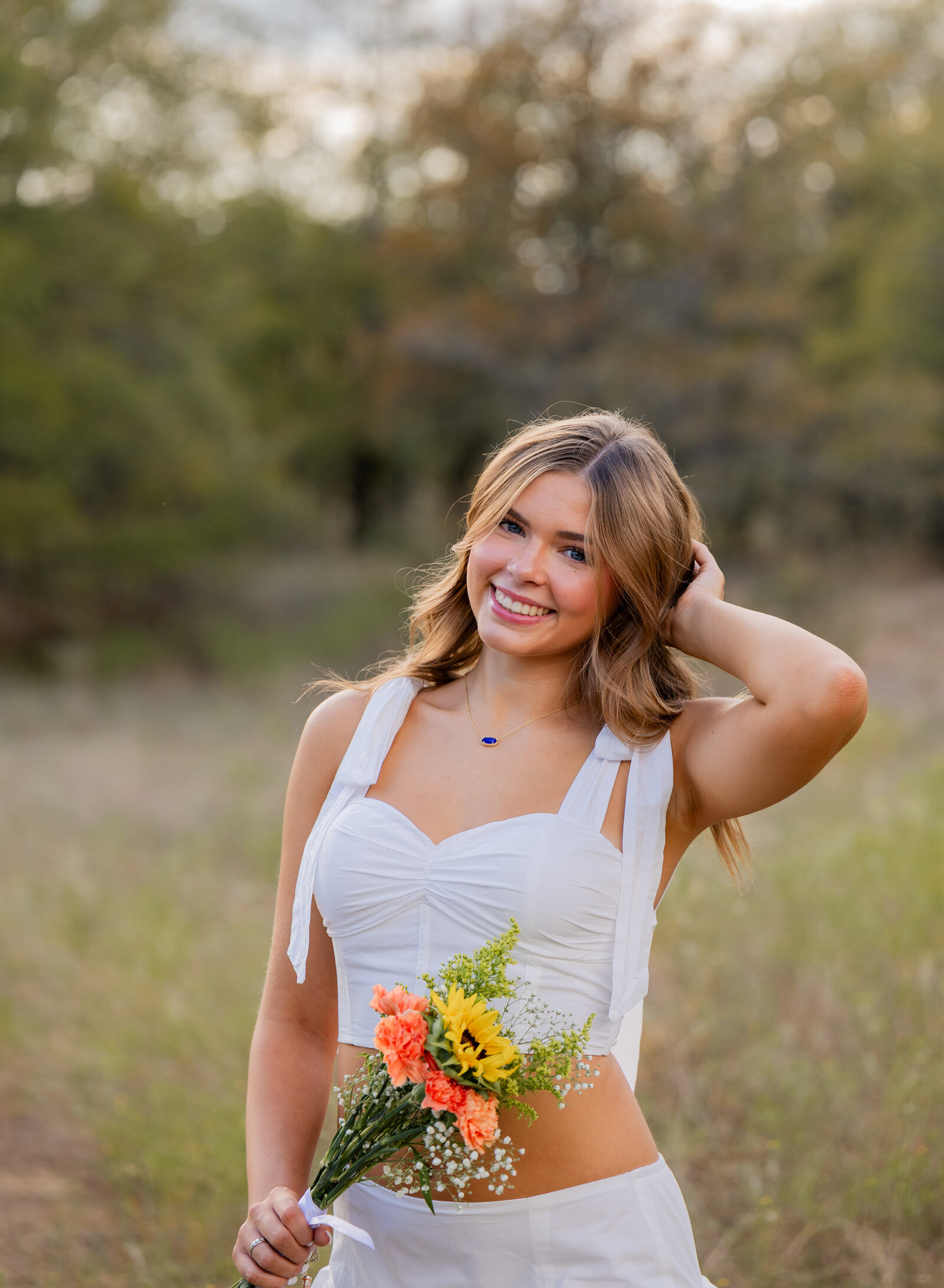 senior in a field with bouquet of flowers