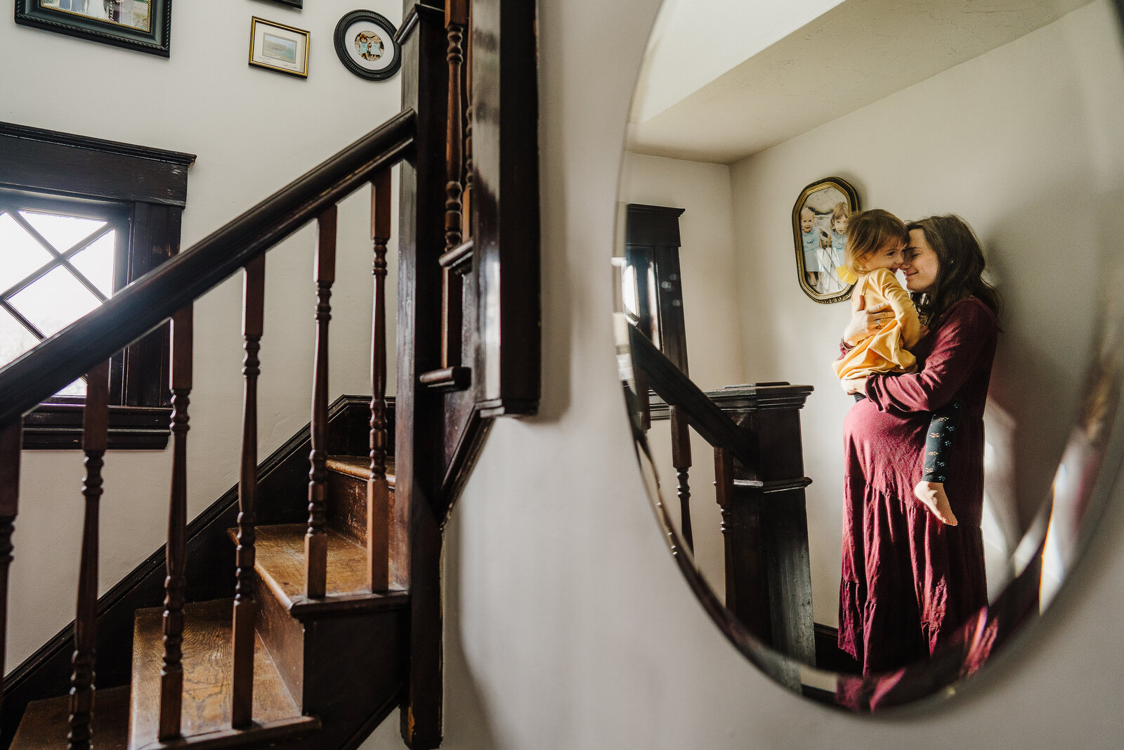 mirror reflection of pregnant woman holding toddler