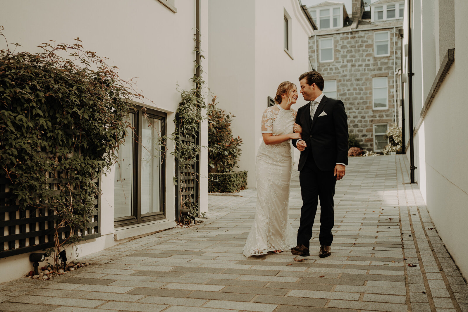 bride and groom walking with linked arms down small courtyard emotional aberdeen wedding photography