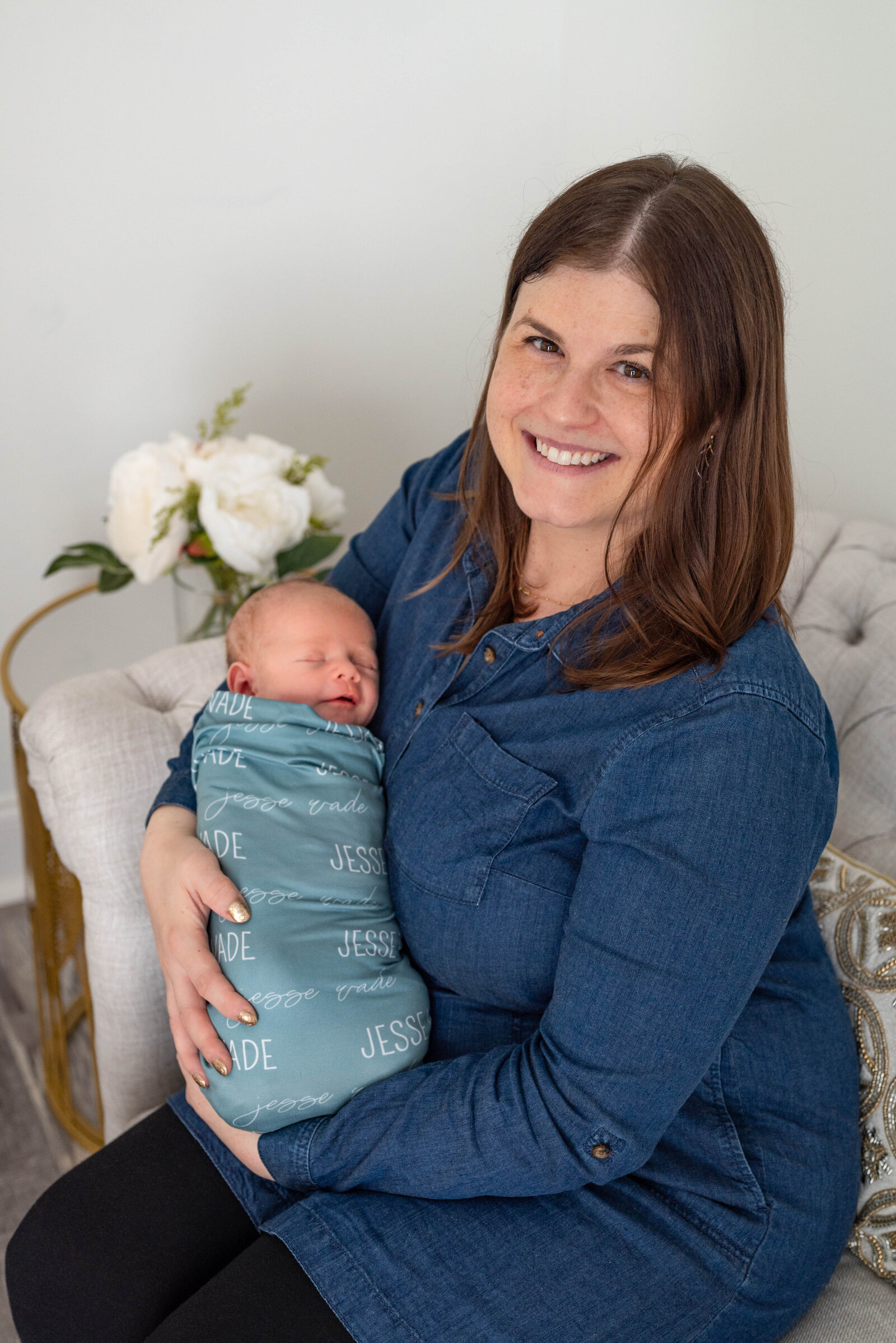 A mom holding her newborn baby  and smiling at a newborn session in Huntsville Alabama