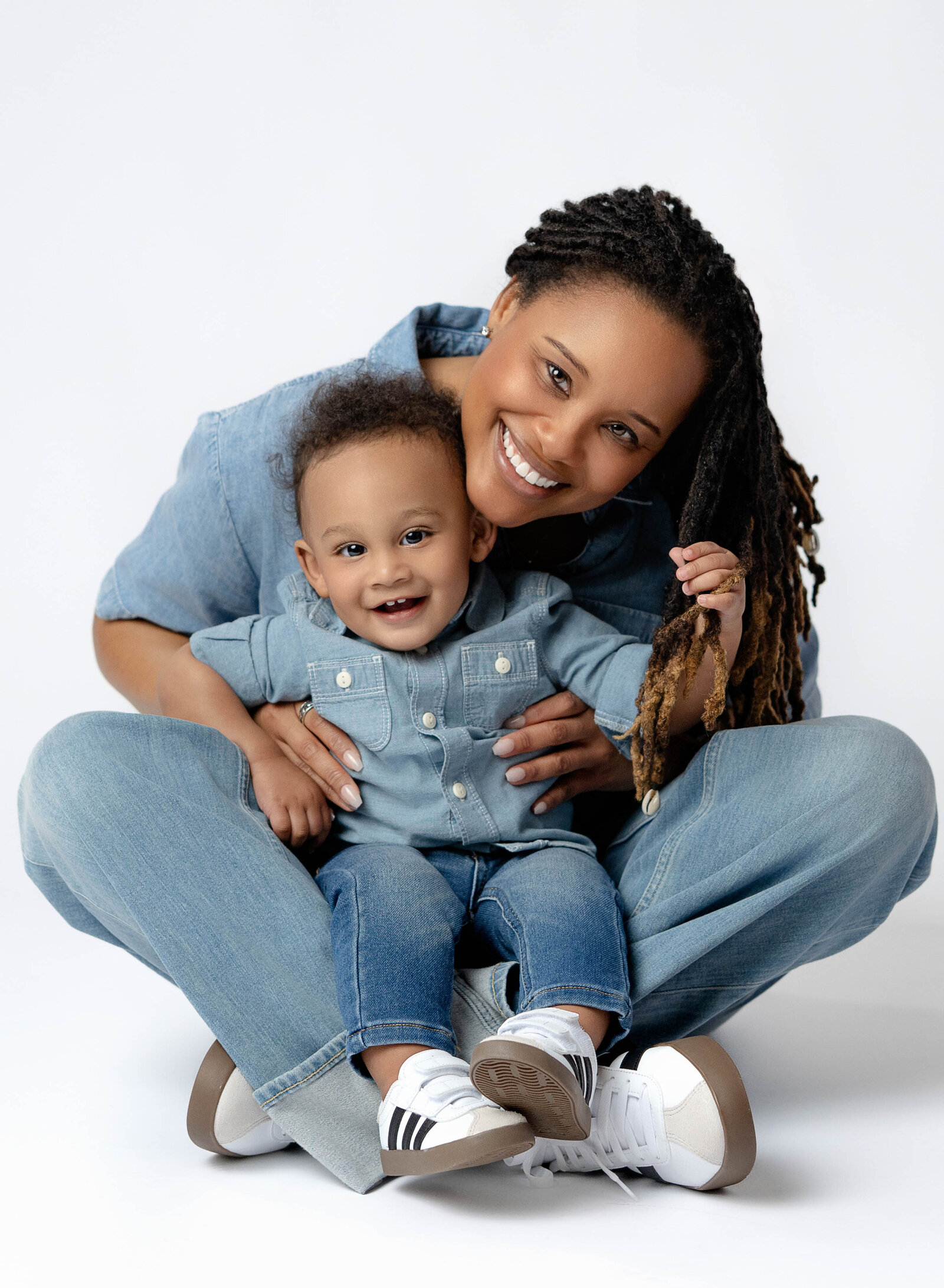 Baby boy sitting in Mom's lap and grabbing her hair. Photographed at Atlanta Family Photo Studio.