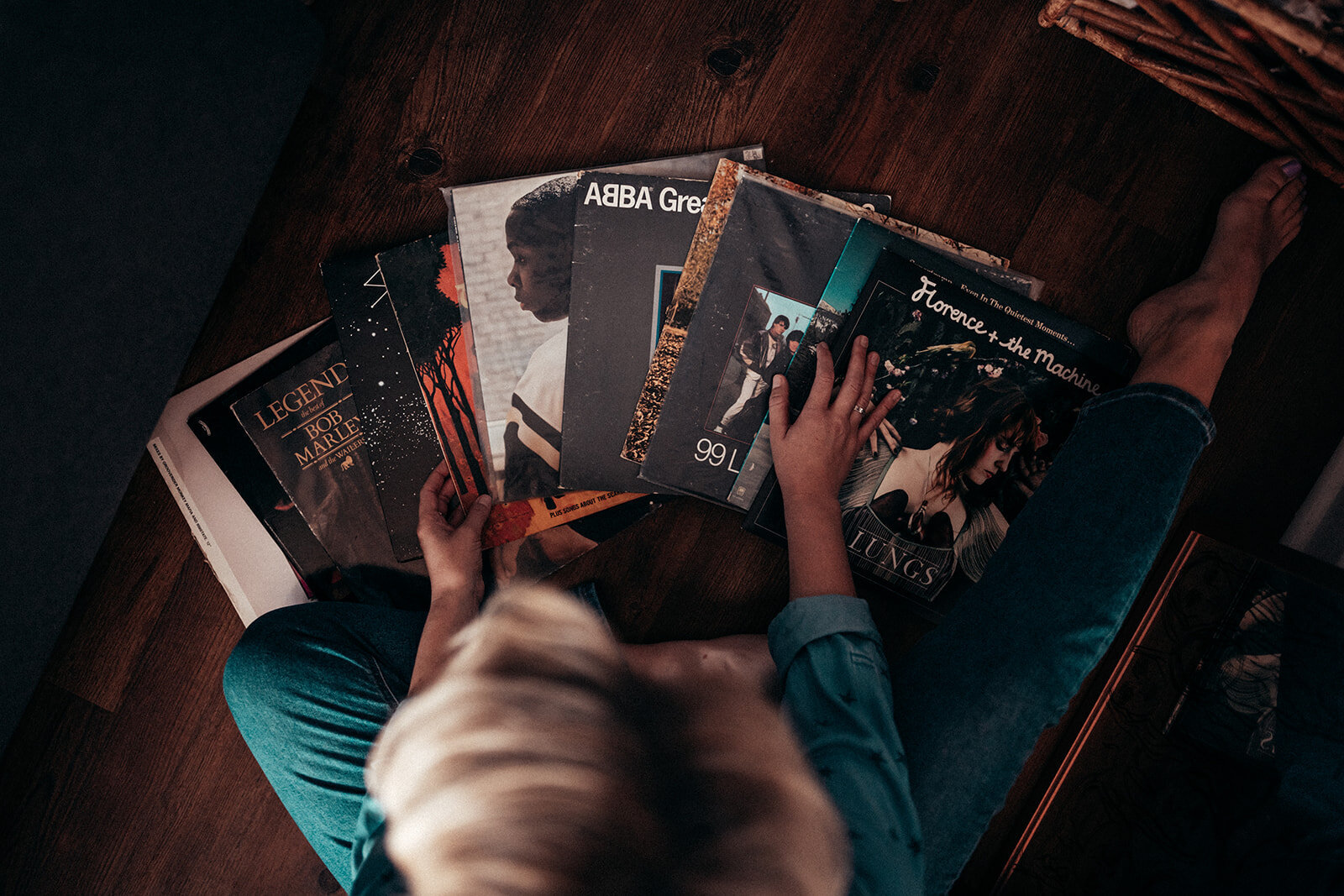 A woman sits amongst vinyl records spread across the floor.