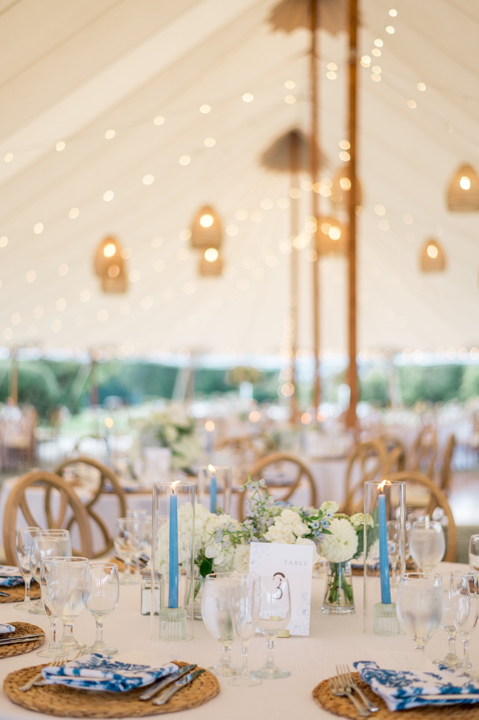 Elegant sailcloth tent wedding reception with coastal décor, soft lighting, and blue accents — luxury New England wedding photography by Sarah Surette Photography.