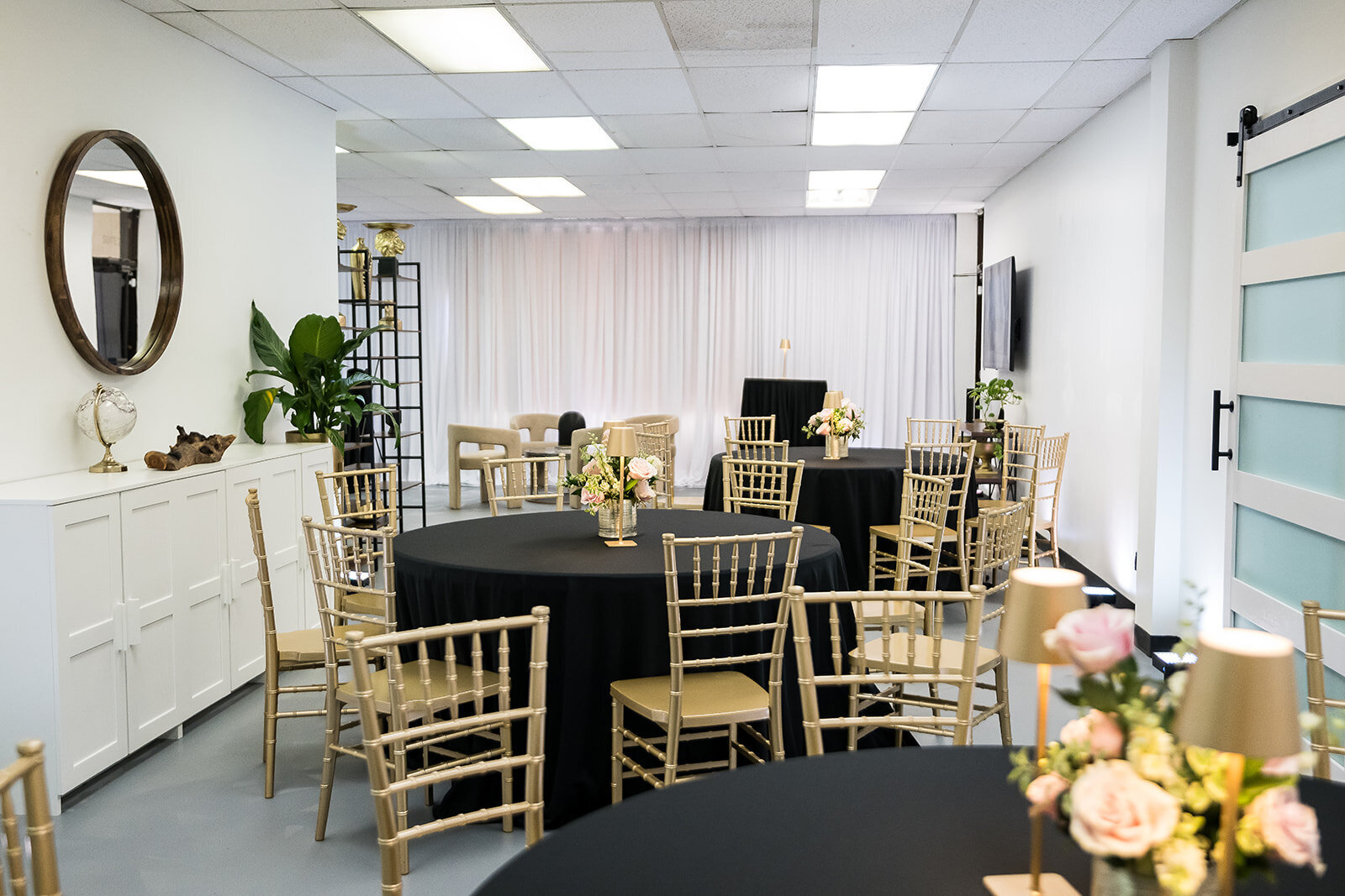 Interior view of The Parlor at Wells in Memphis, featuring gold chiavari chairs, black round table linens, lounge seating, and decorative shelving—perfect for intimate events, workshops, and creative gatherings.