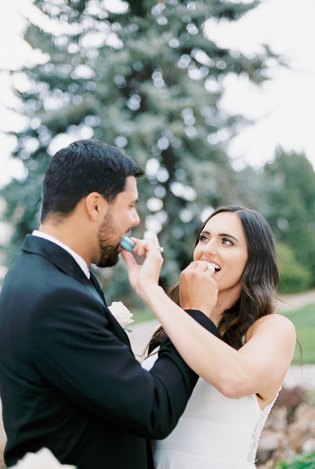 Bride and groom feeding each other macarons at Cottage at Riverbend Wedding by the Best Boise Wedding Photographers
