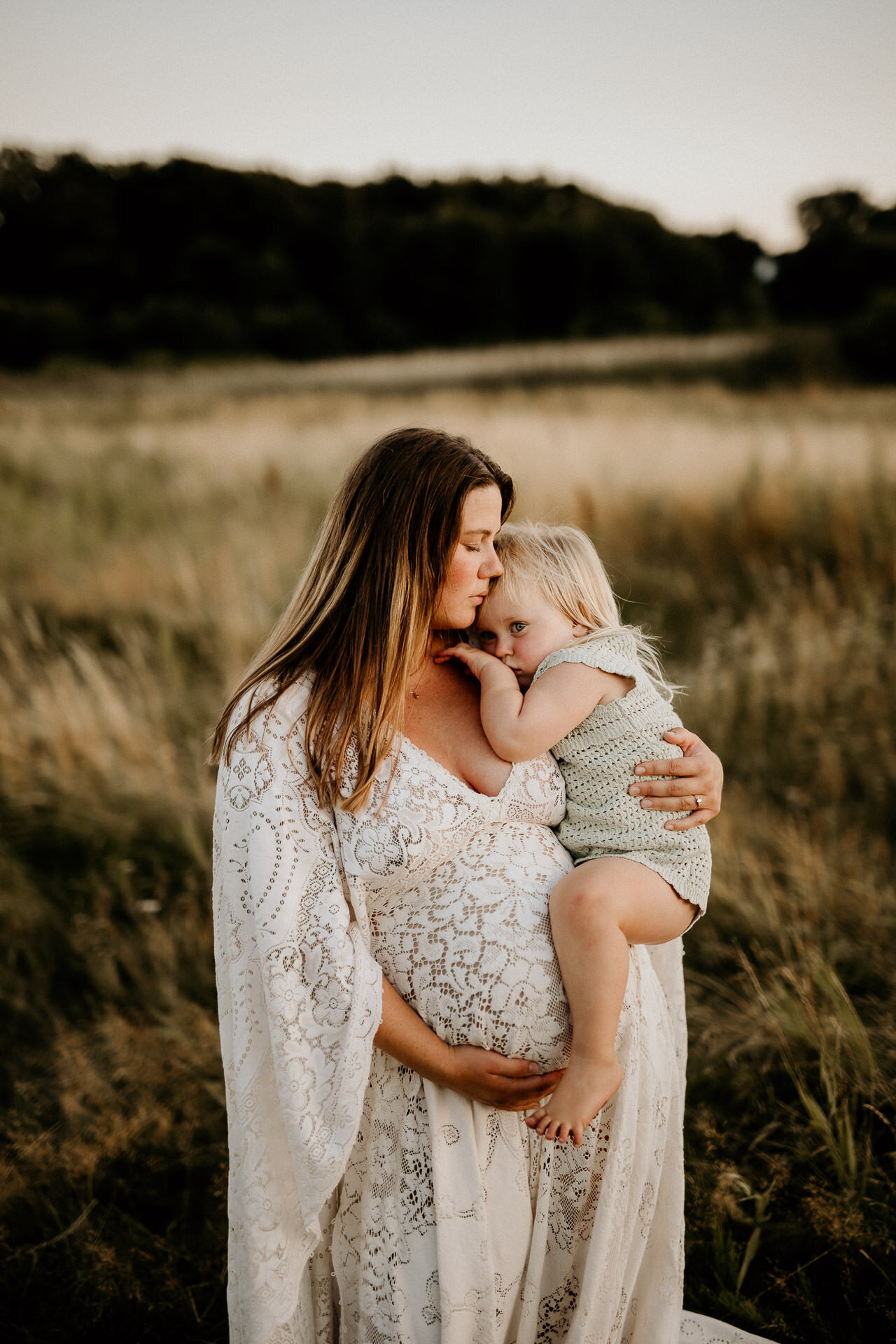 en gravid kvinna håller om sin dotter på ett fält