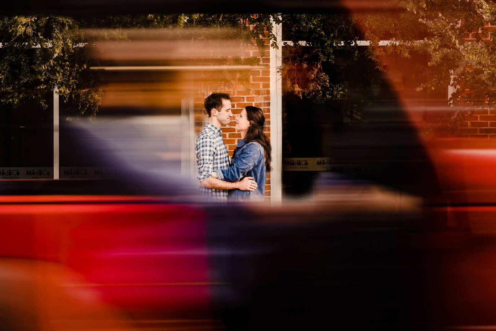 car drives by a couple embracing during engagement photos