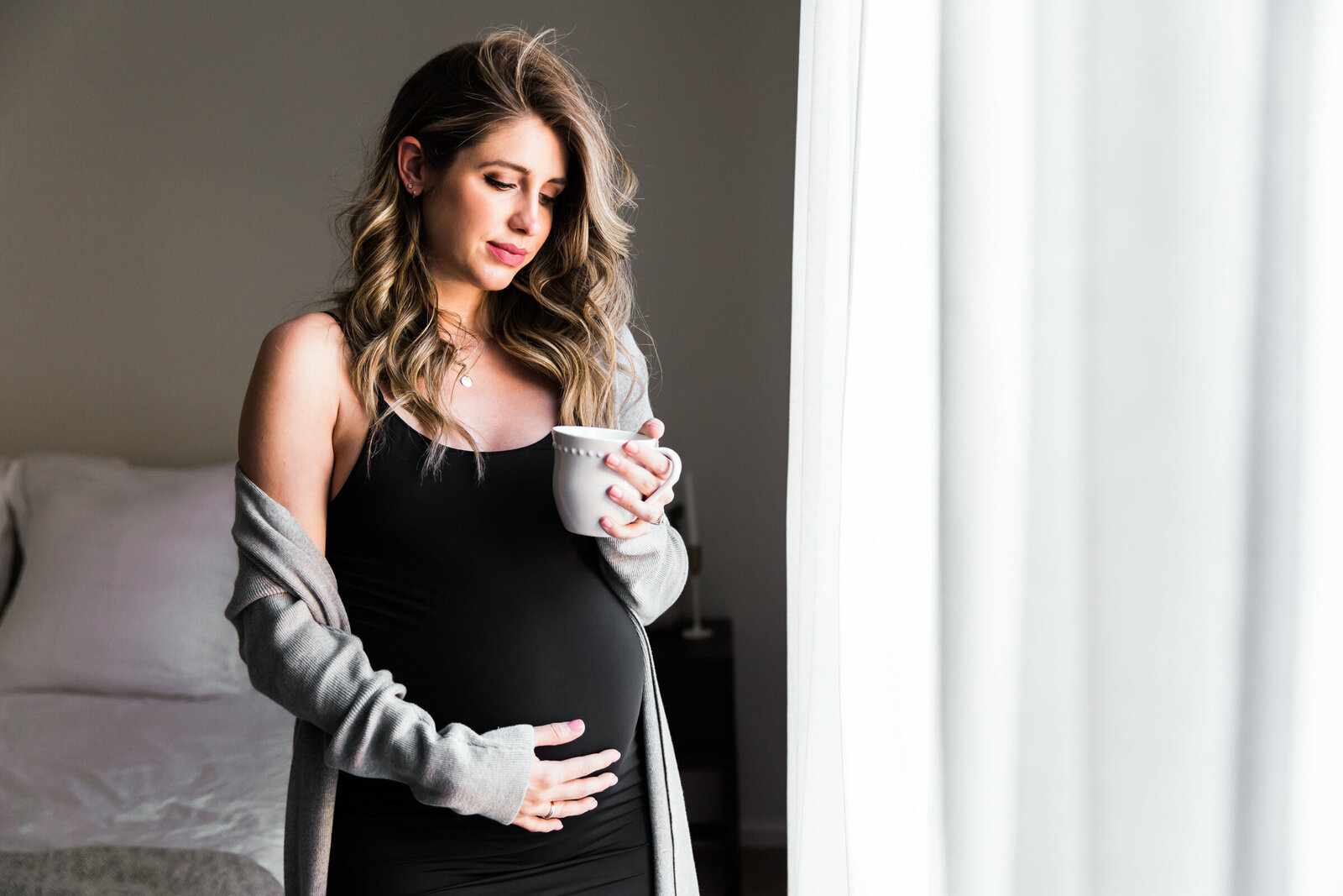 mom to be holding bump in bedroom