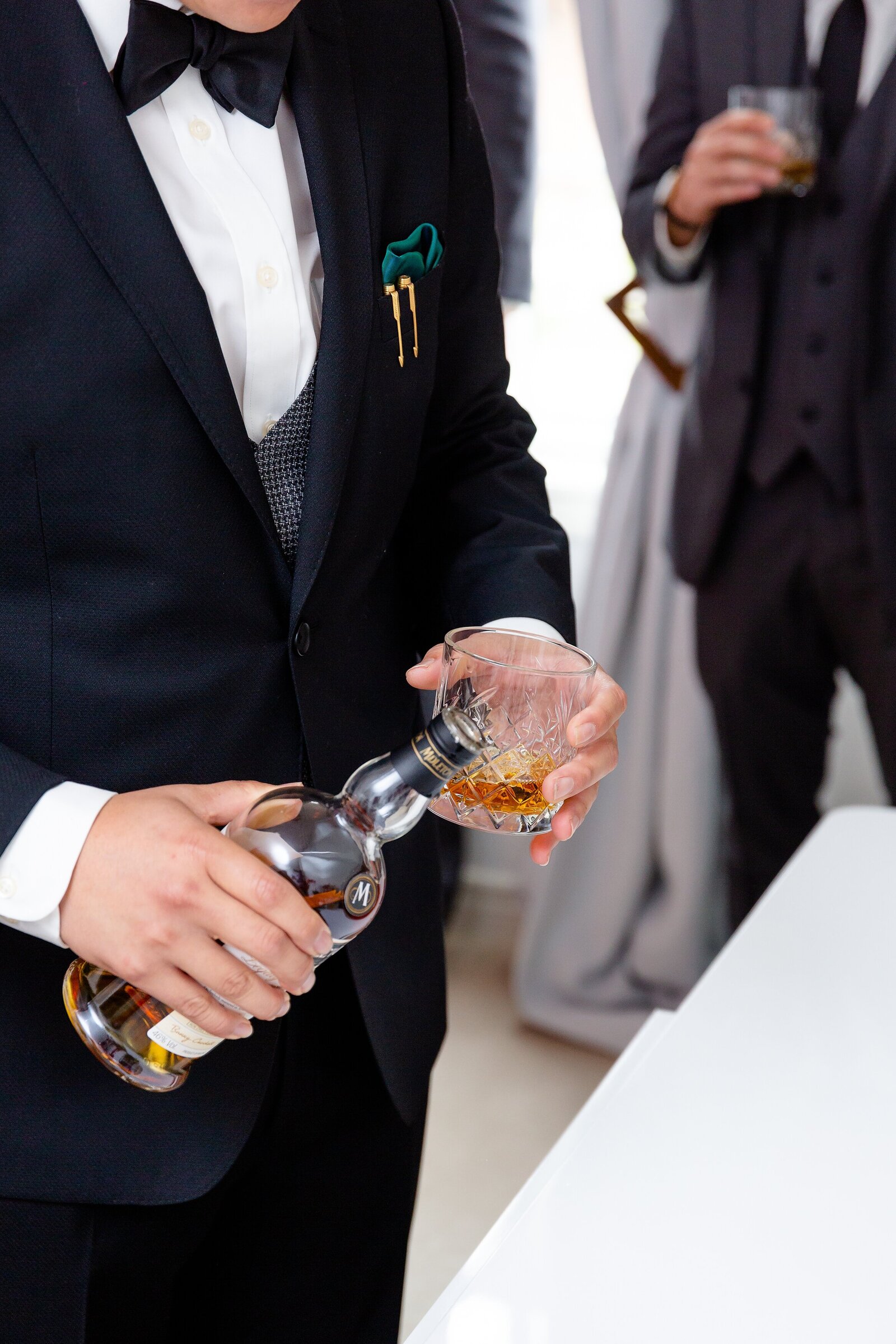 Groom pours glasses of whiskey for him and his groomsmen