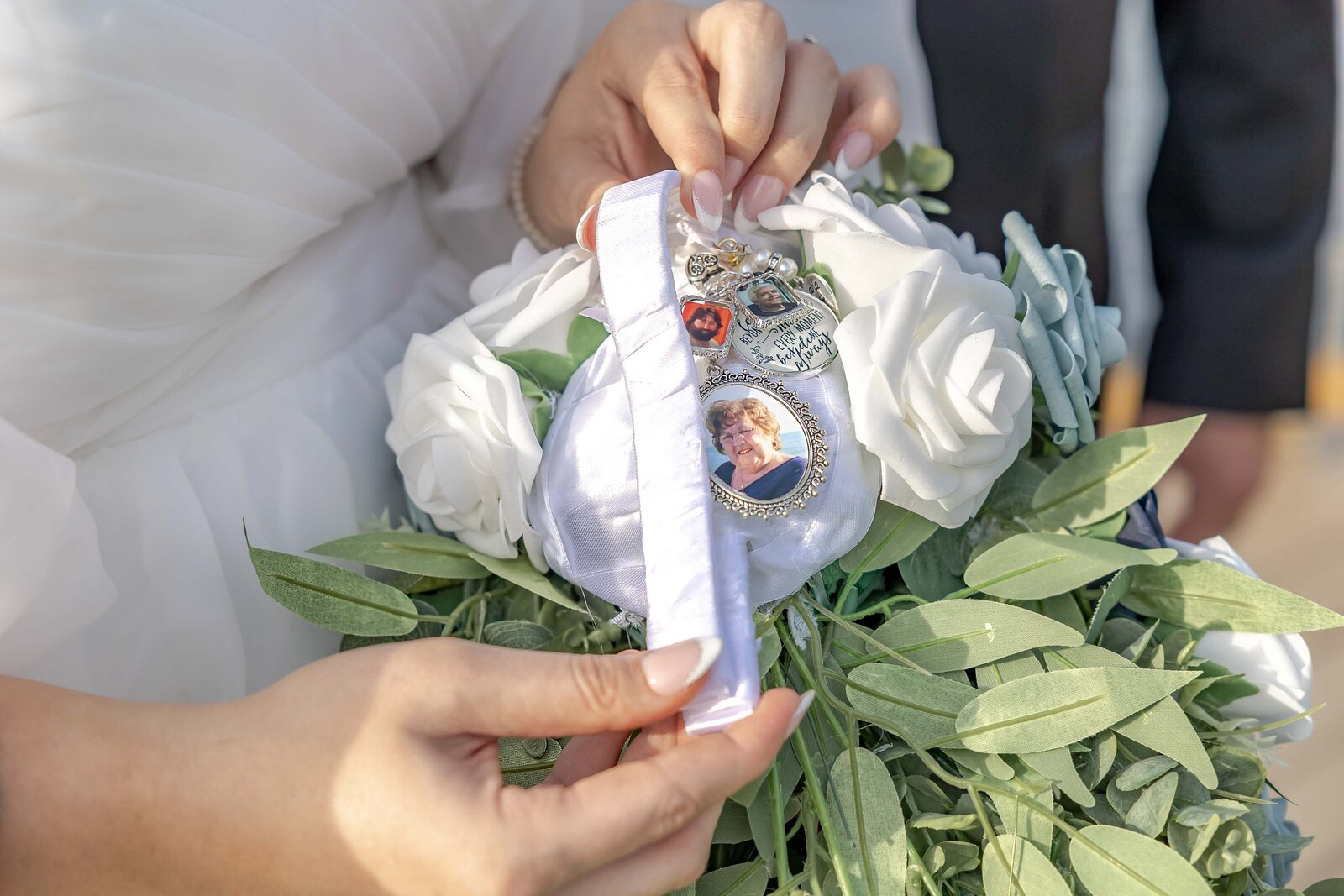 The bride holds her bouquet adorned with a sentimental charm featuring a family photo and ribbon, captured during a Wilmington, NC wedding, showcasing meaningful and personalized wedding details.