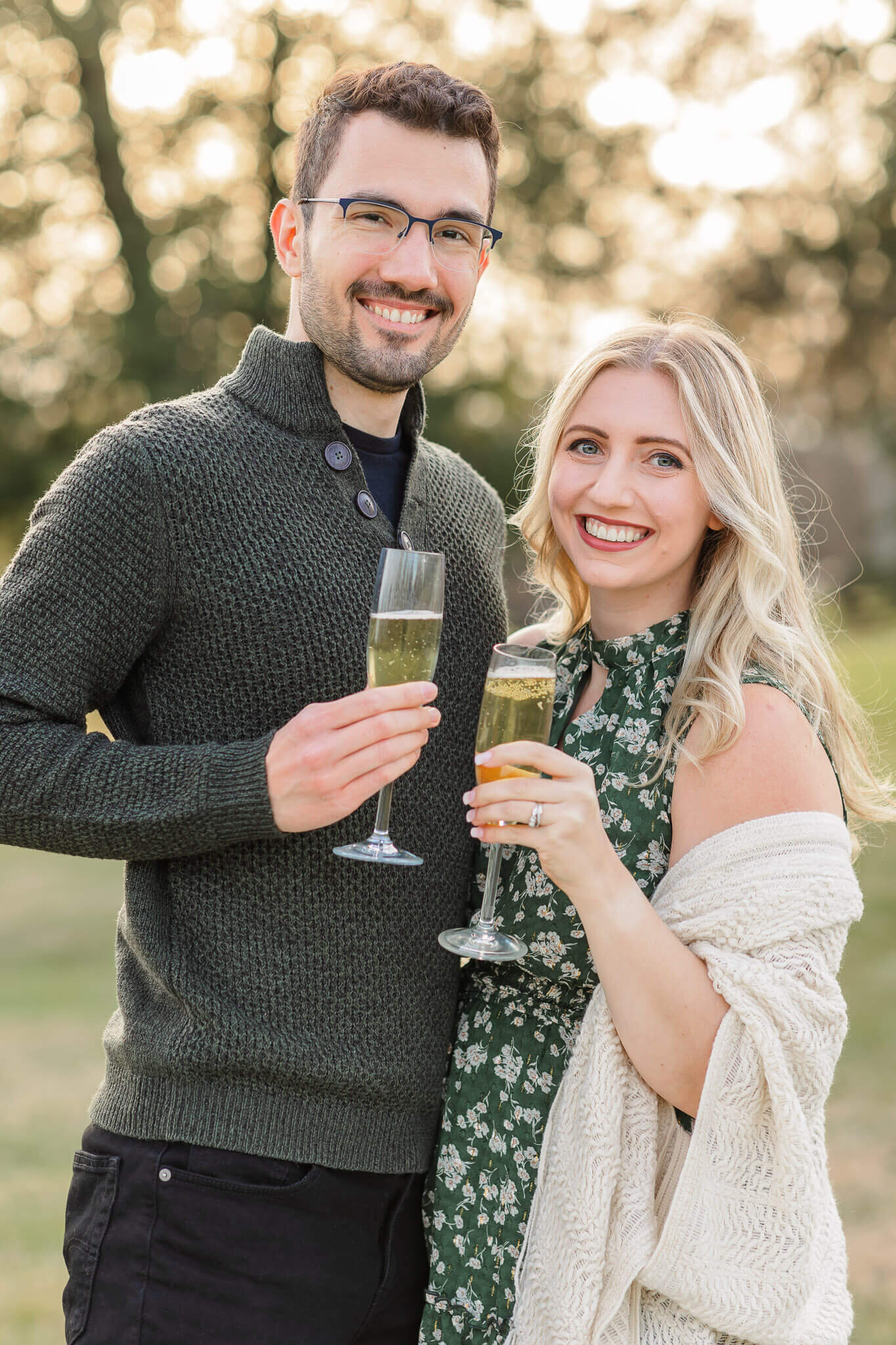 A mom and dad smiling at the camera holding their apple cider.