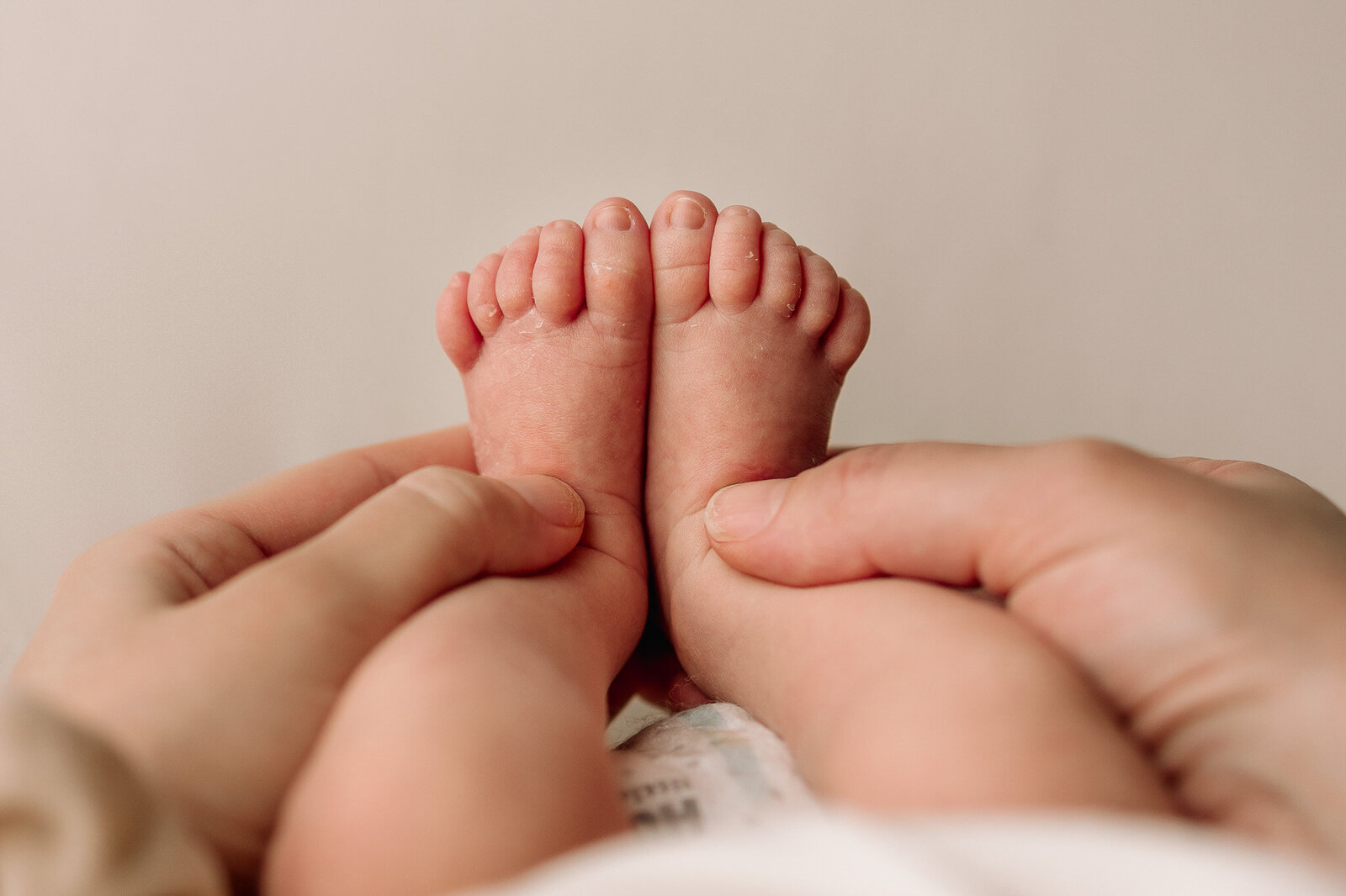 Close up photo of newborn toes against a cream backdrop 
