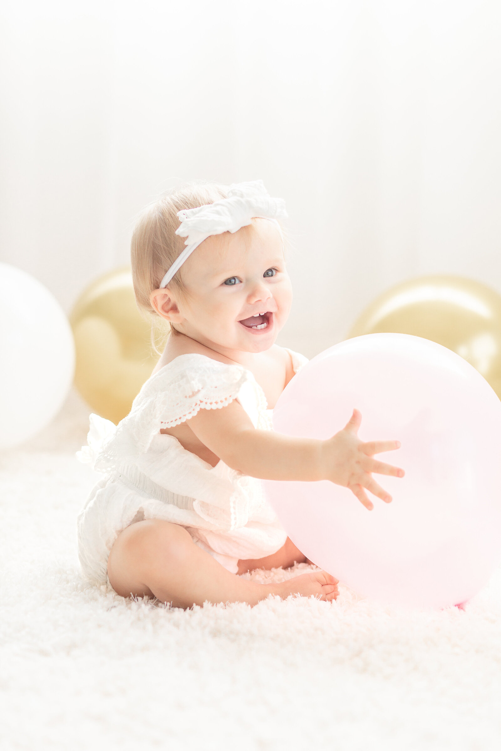 Plymouth Michigan Newborn Photographer captures baby girl with balloons at her first birthday cake smash session at Studio Neue