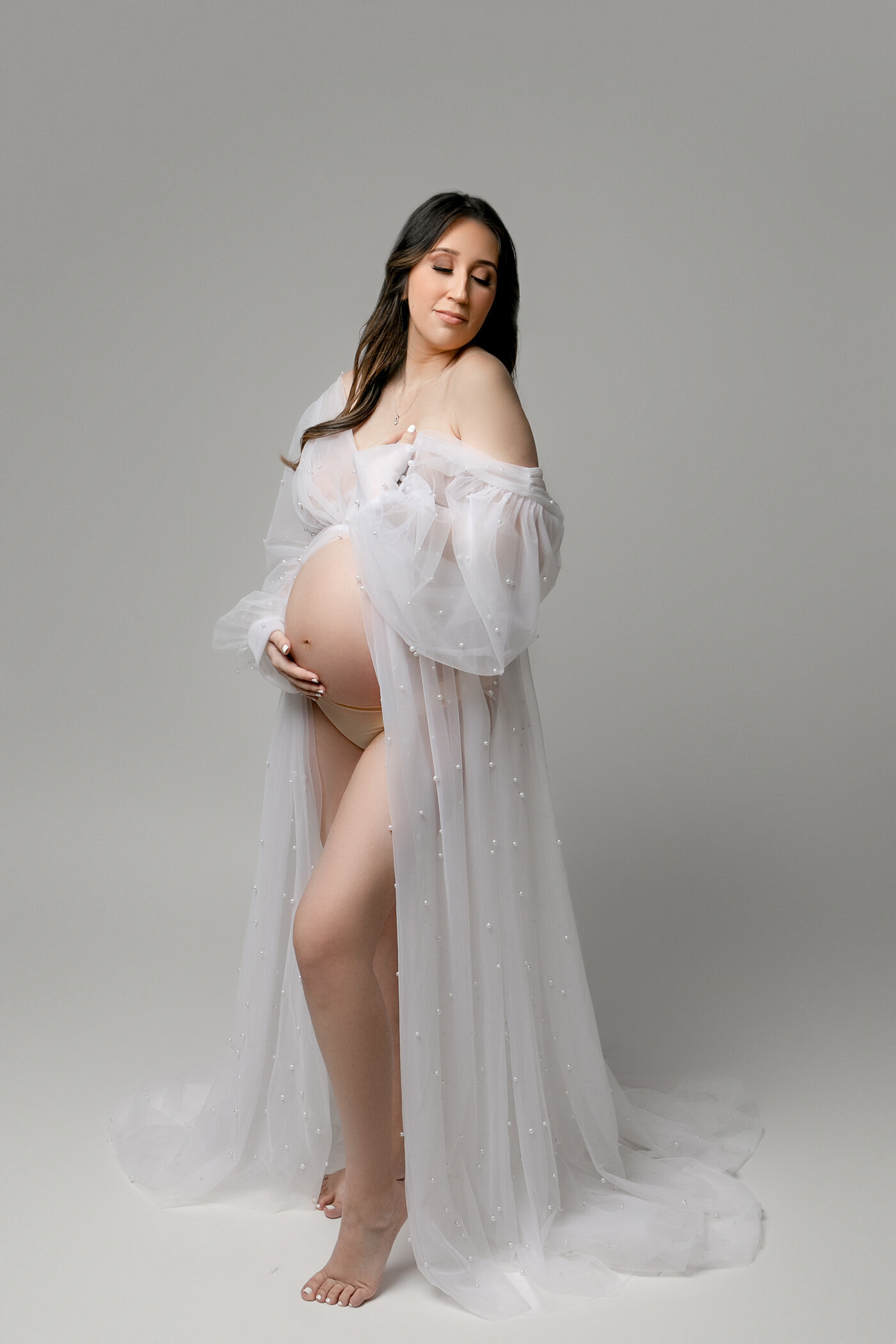 Expectant mother dressed in a whote sheer pearl embellished maternity gown. classic, timeless, pregnancy photos in fresno, clovis, california