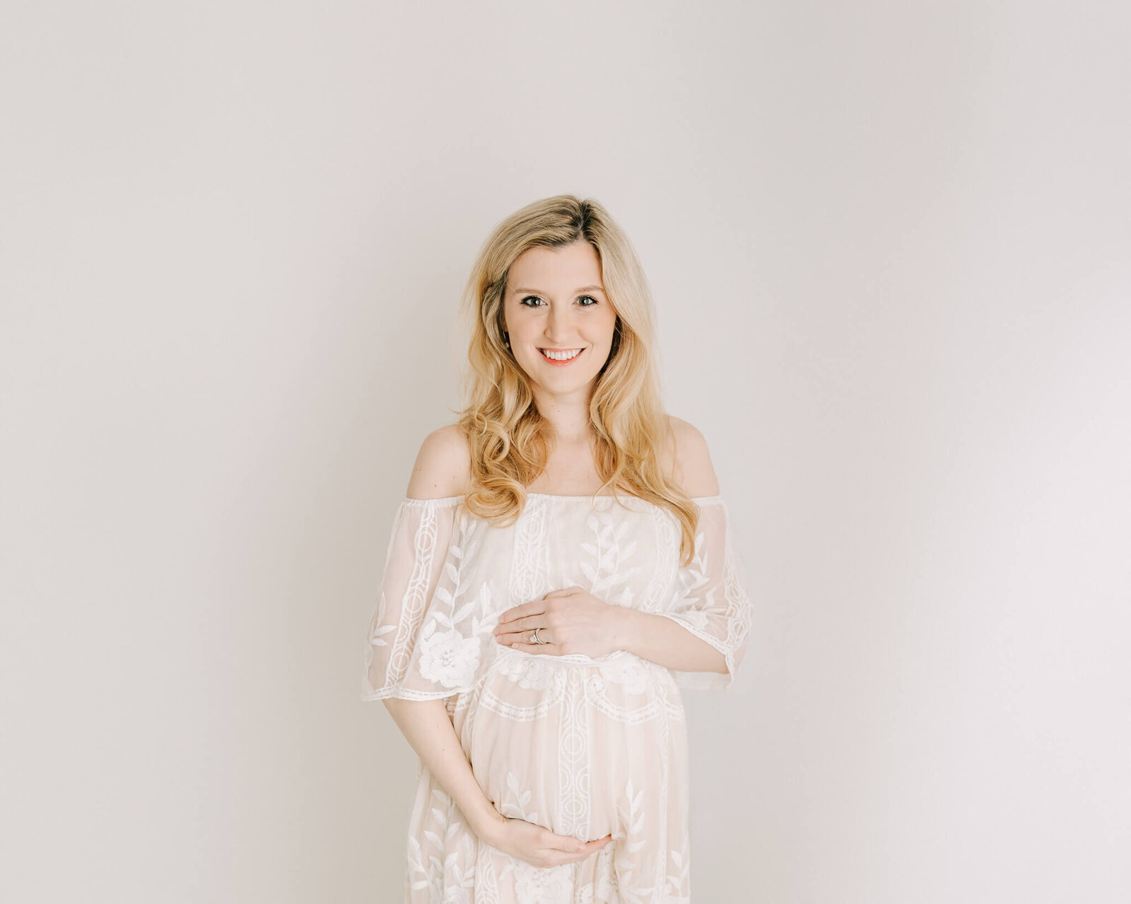 Expecting Mom in cream dress cradling her baby bump at Maternity session with Molly Berry Photography.
