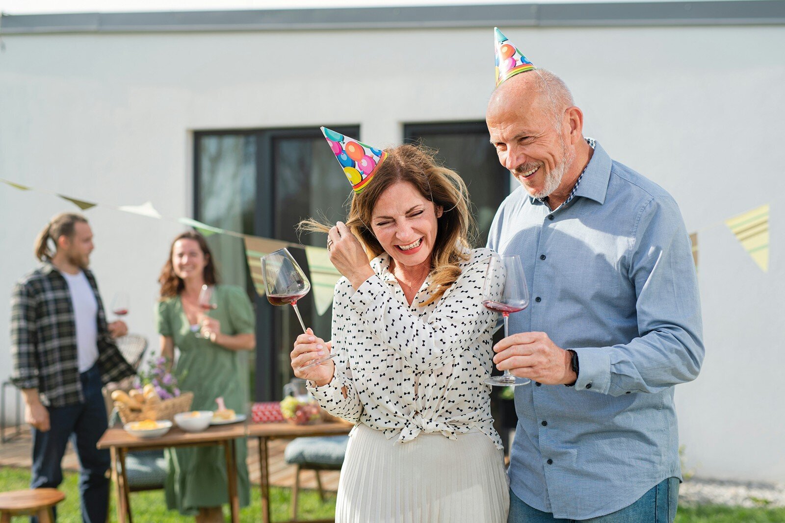 Older couple laughing and wearing party hats at a birthday celebration
