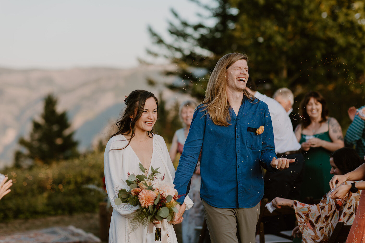 Newlyweds laugh while walking up the aisle after their outdoor wedding ceremony