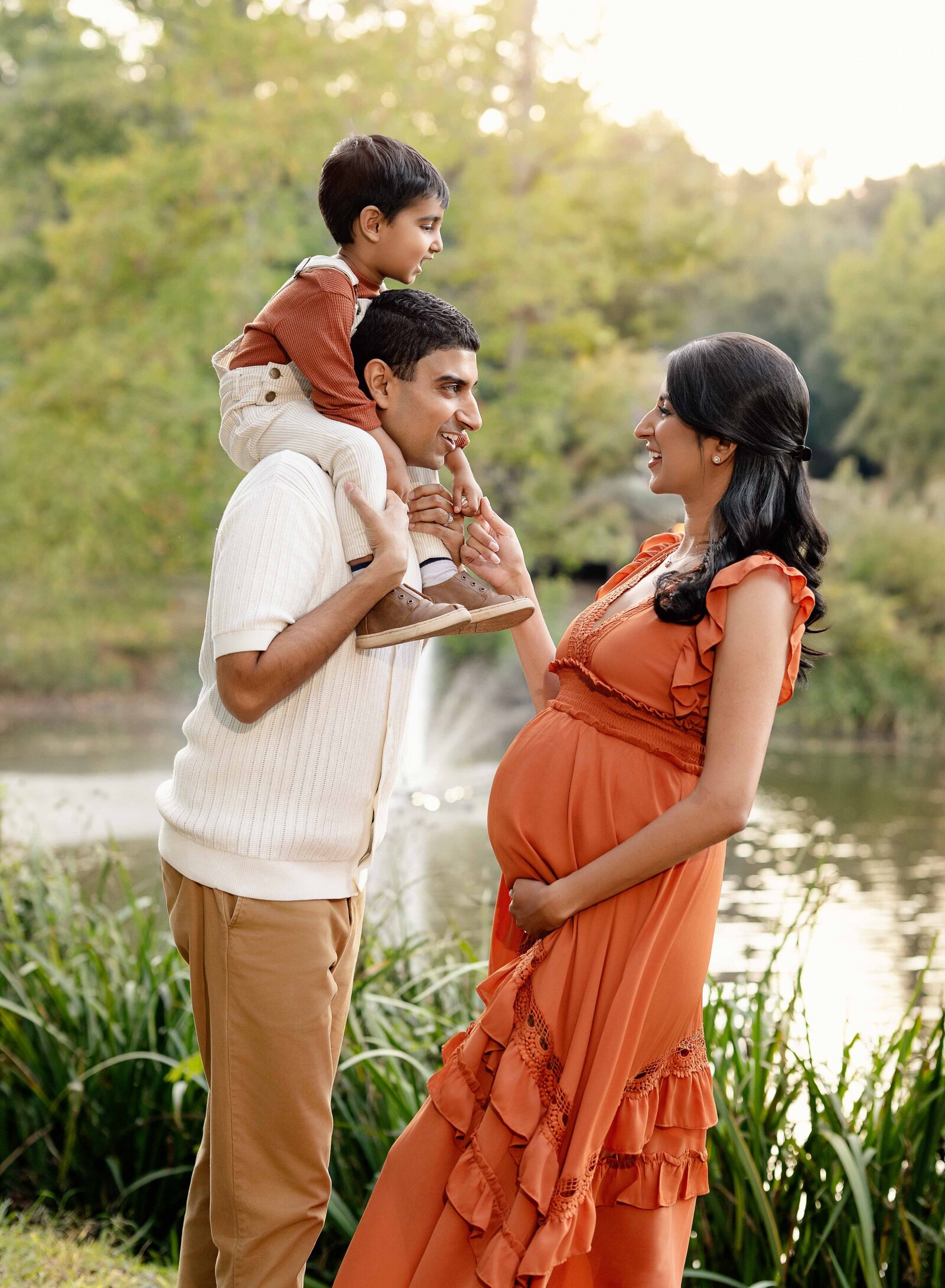 Toddler boy on Dad's shoulders with mom holding his hand and smiling at them. 