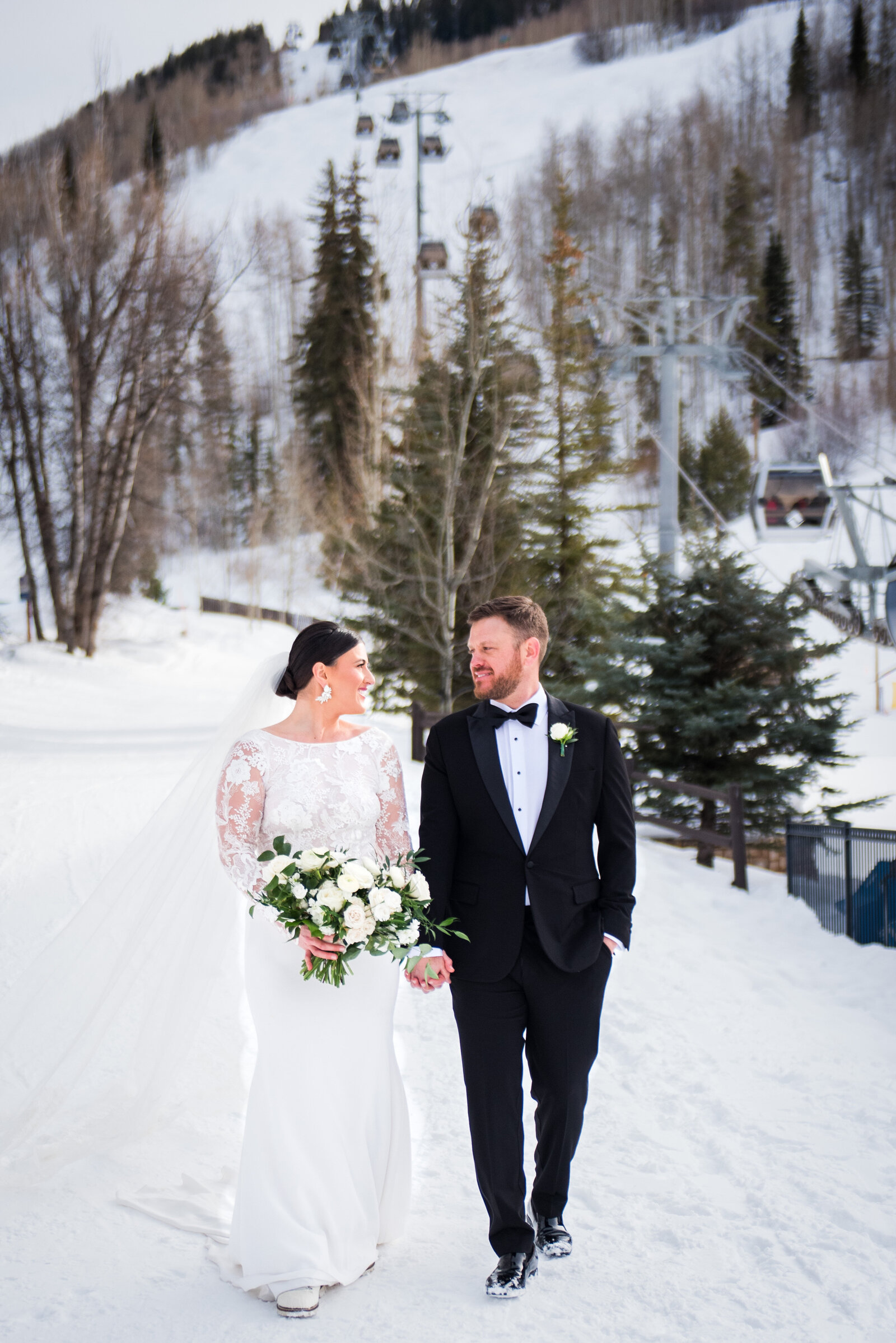 Bride and group walk toward the camera hand-in-hand in a snowy Colorado mountain wedding.