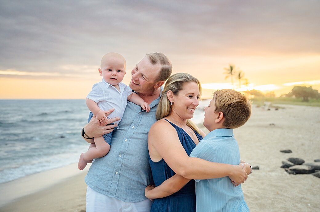 family snuggling at the beach at sunset