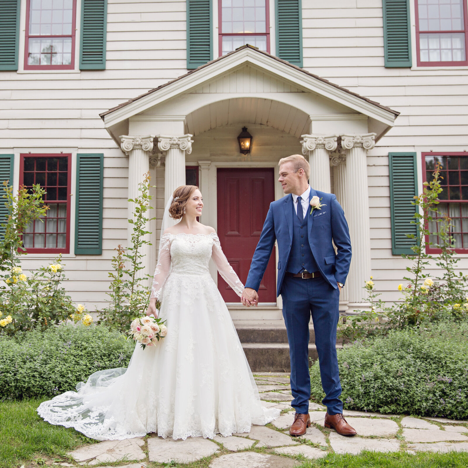 wedding couple holding hands in front of Battlefield Museum Park in Hamilton Stoney Creek