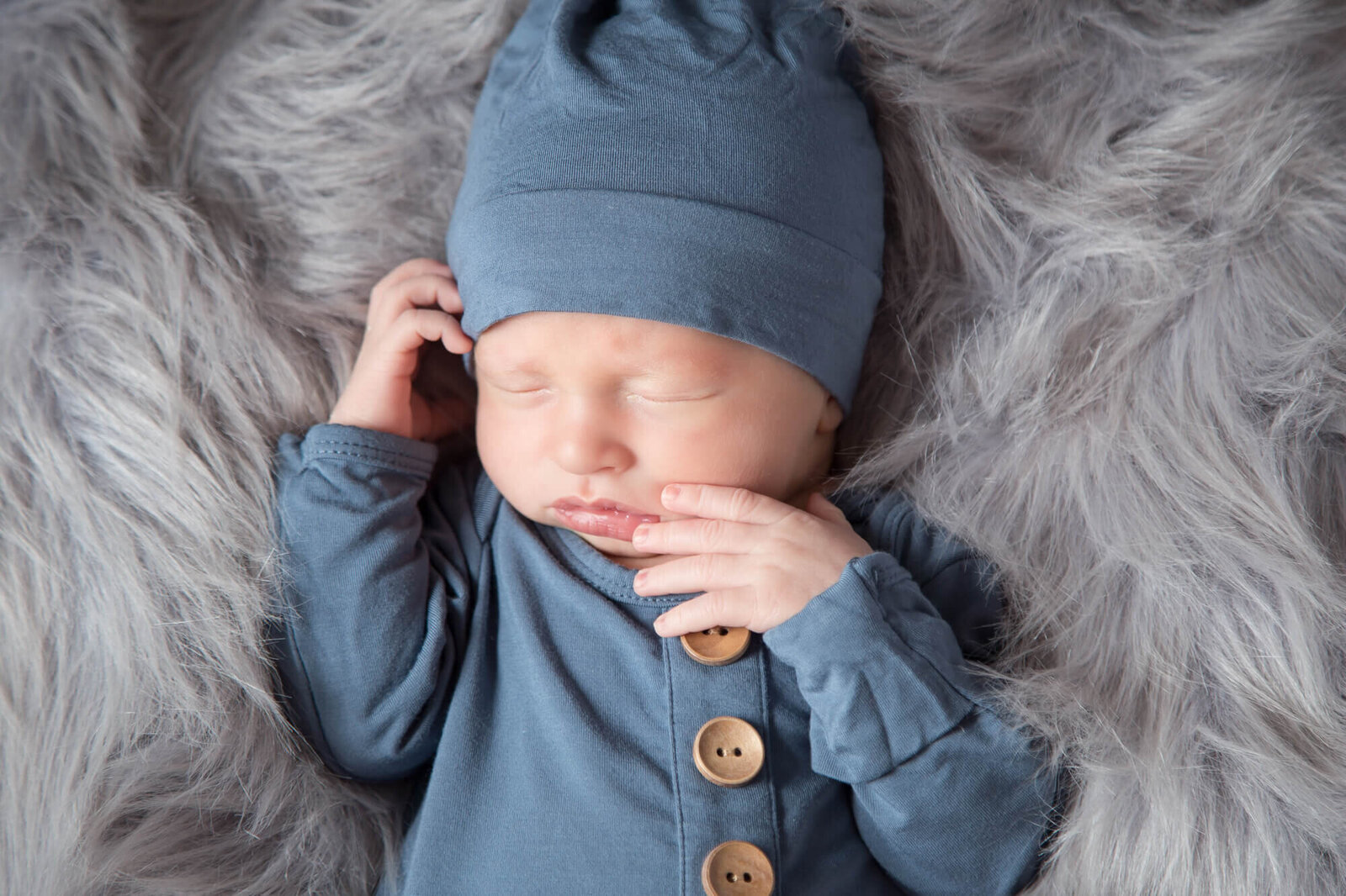 Newborn baby boy on a gray fur blanket