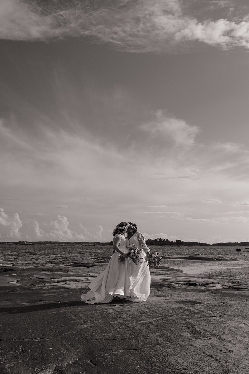 HBTQI+ bröllop. Brudpar står och kysser varandra vid havet