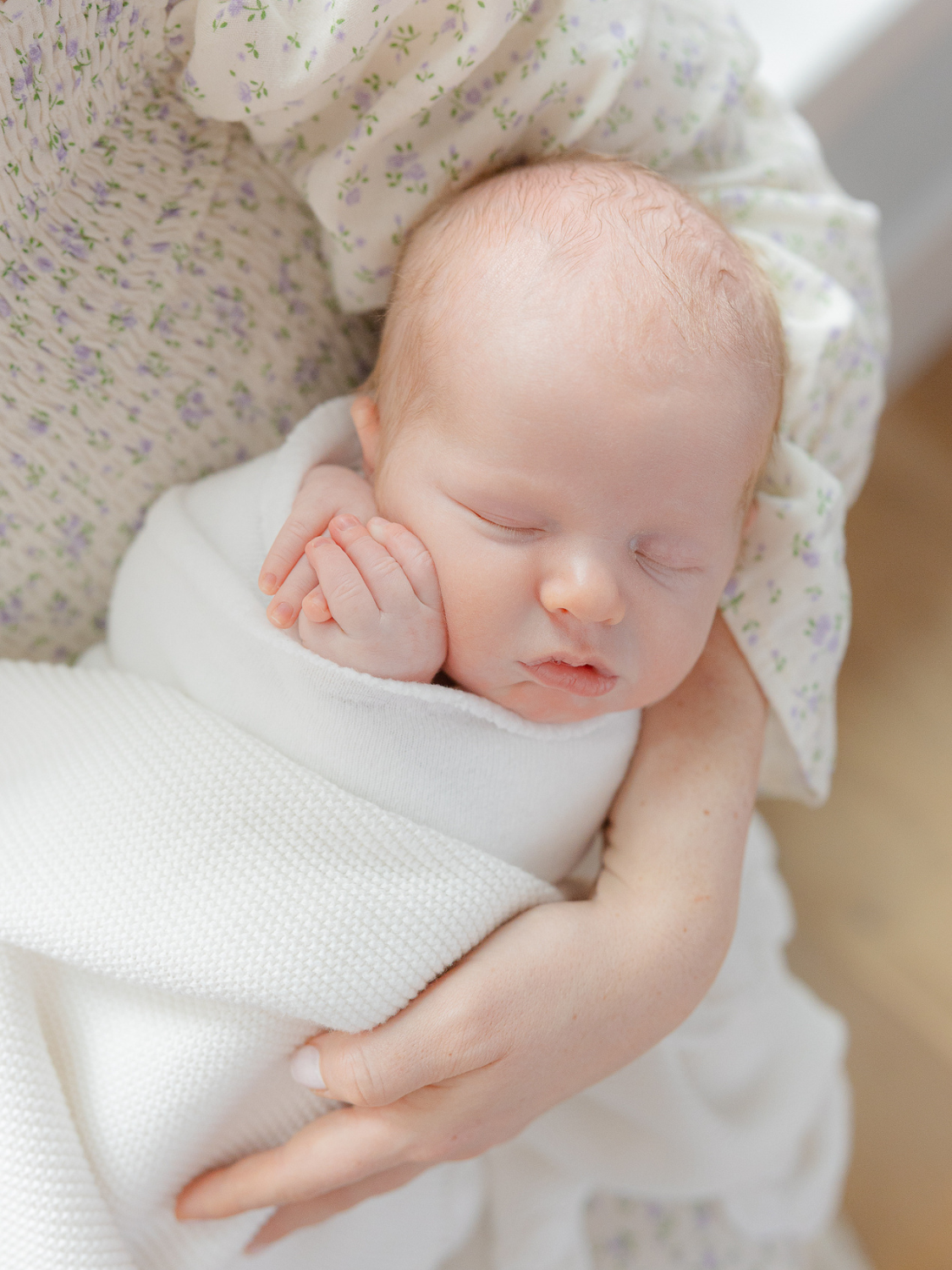 sleeping baby wrapped in white blanket sleeps peacefully in mom's arms