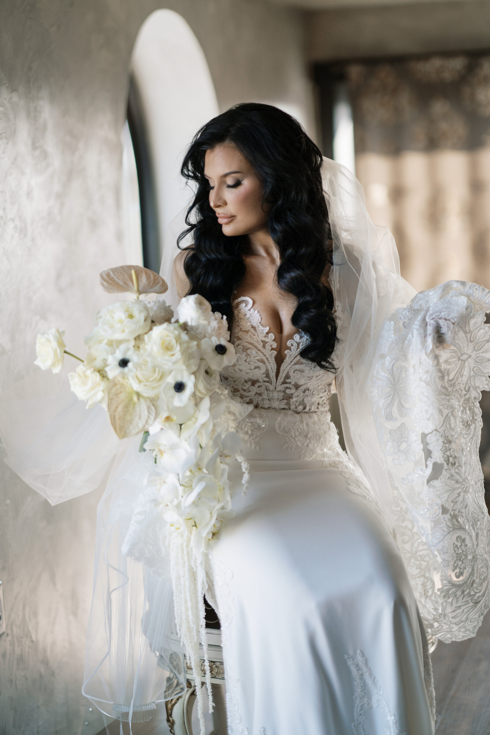 Bride in beaded gown holding white bouquet, wearing sleek, polished waves styled by Promise Artistry.