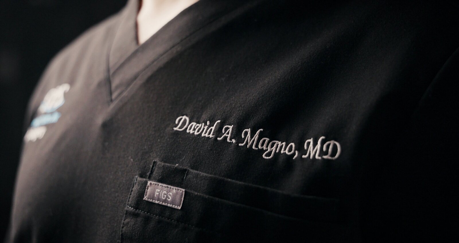 Embroidered surgeon name on a black scrub top
