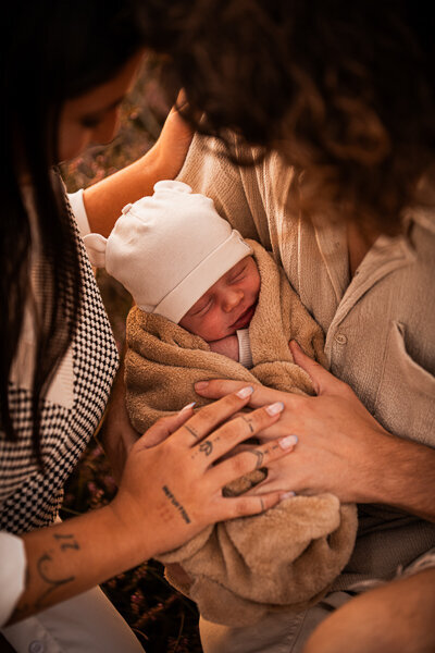 Een newborn fotoshoot in de natuur, omringt door de ouders en trouwe hond