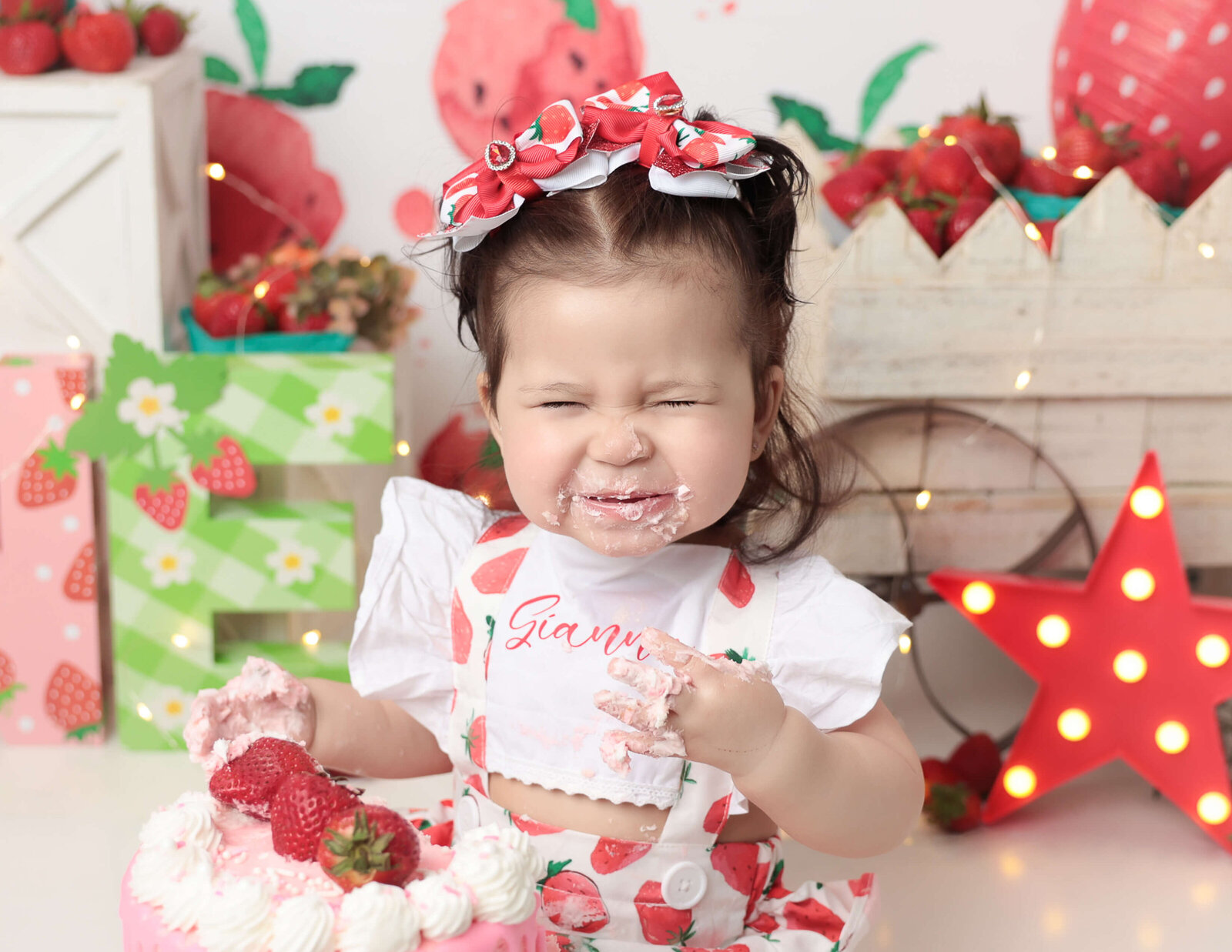 Girl with srunchy nose, strawberry theme cake smash.