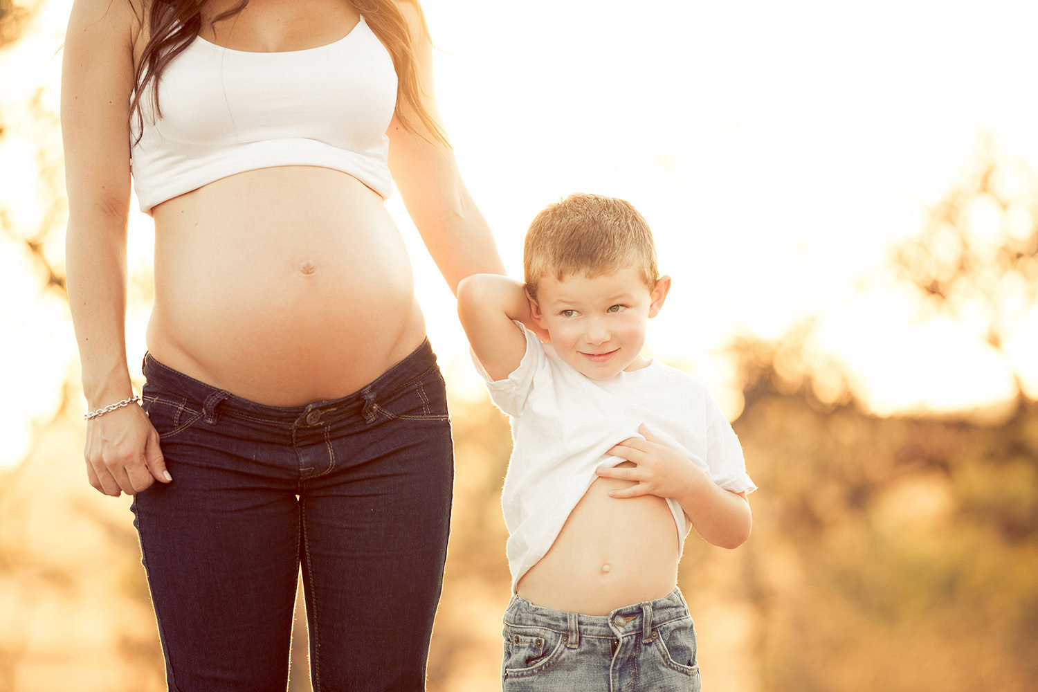 Toddler comparing bellies with his pregnant Mother in San Diego.