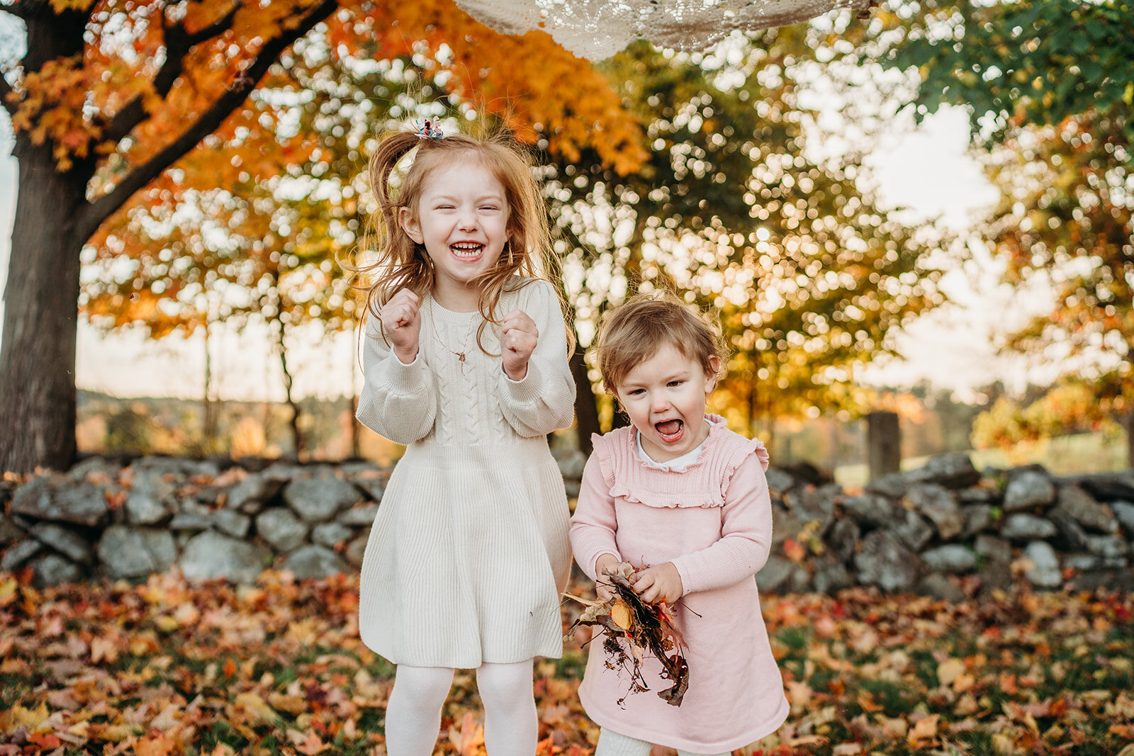 girls shriek holding autumn leaves