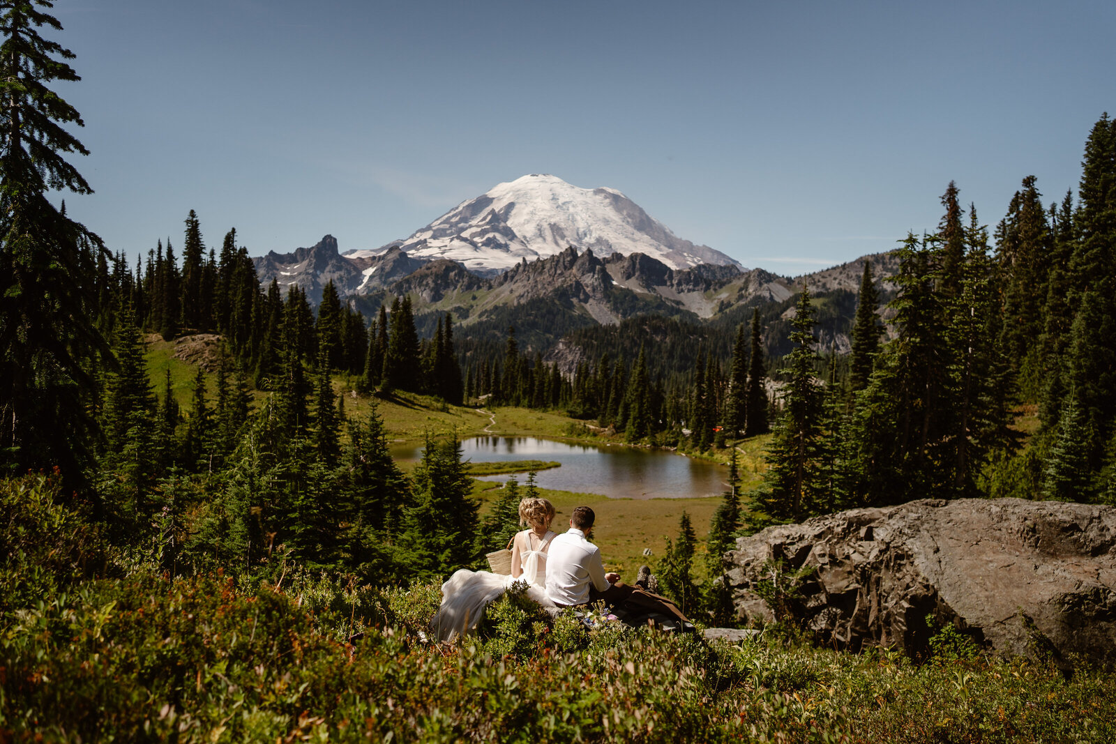 a bride and groom sit together overlooking Mount Rainier during their washington elopement