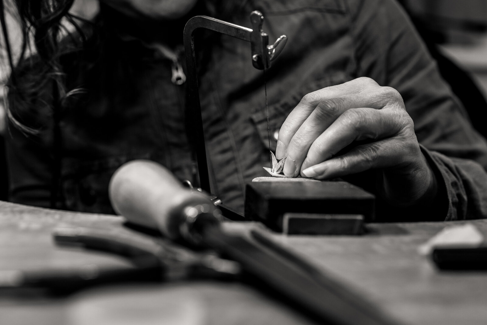 A jewelry artist's hand shaping a silver creation.