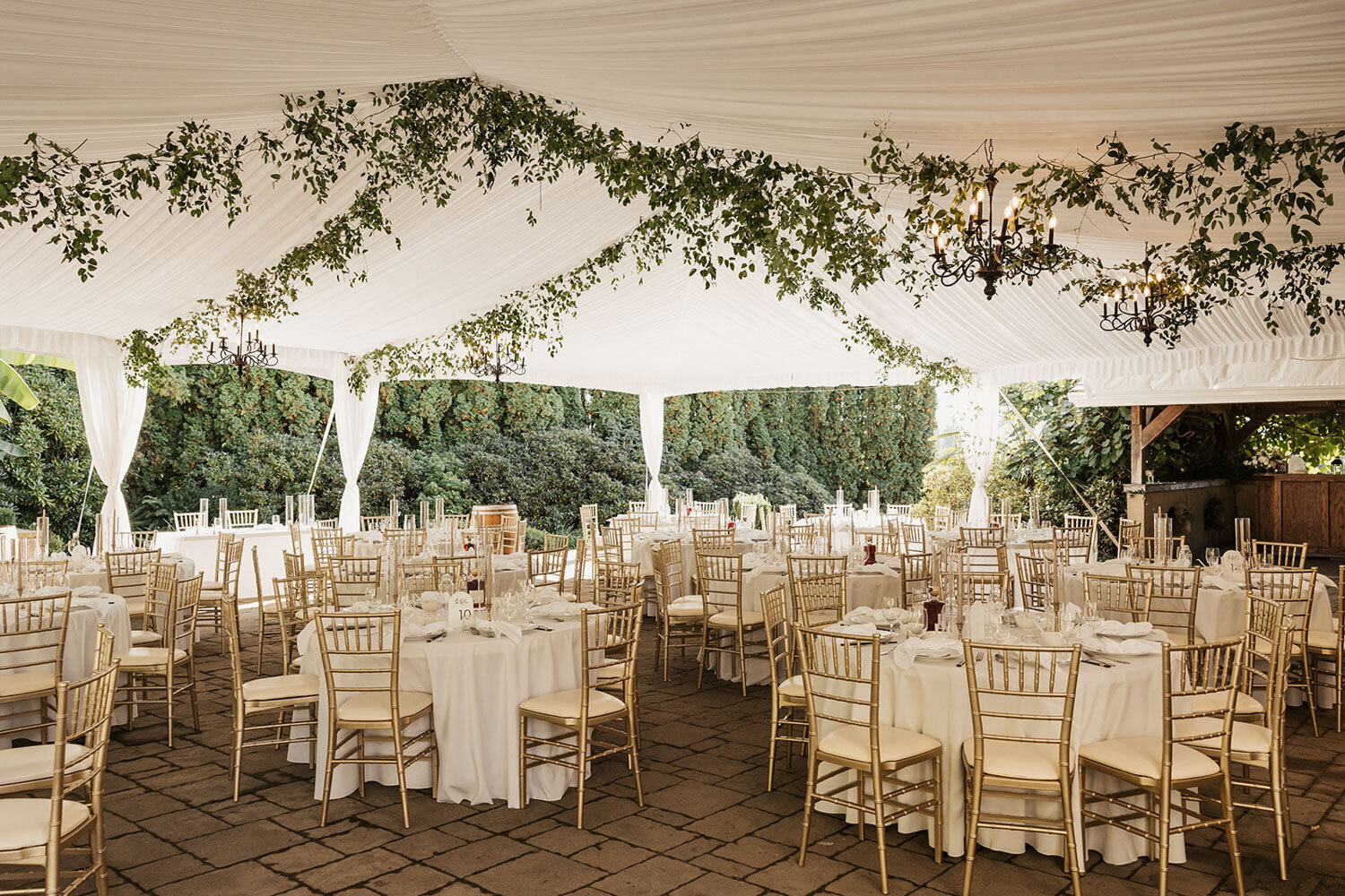 Reception tent featuring gold chairs and greenery