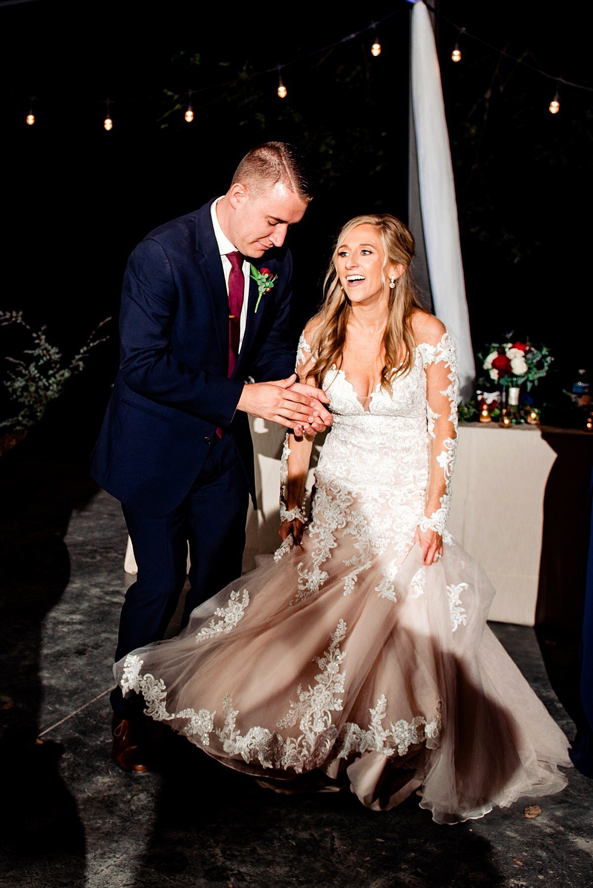The bride in a long lace wedding gown and the groom in a dark navy suit dance all night long