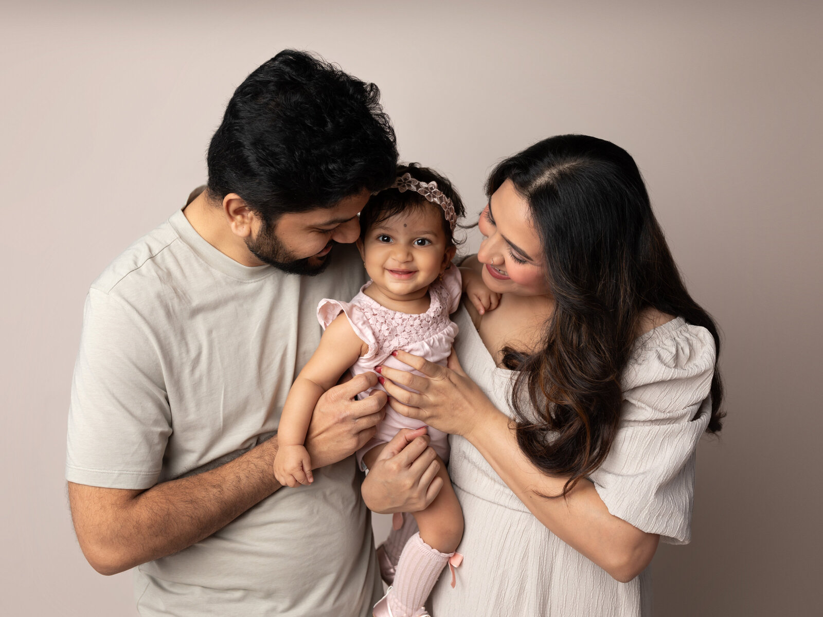 parents holding one year old daughter for studio portraits 