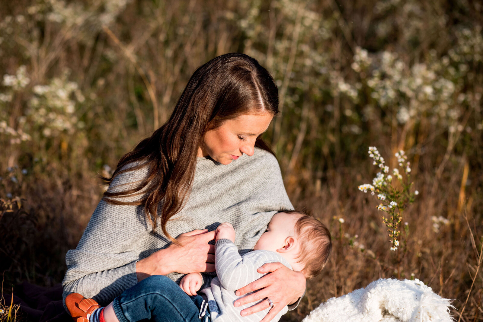 mother nurses her young son in a field of wildflowers