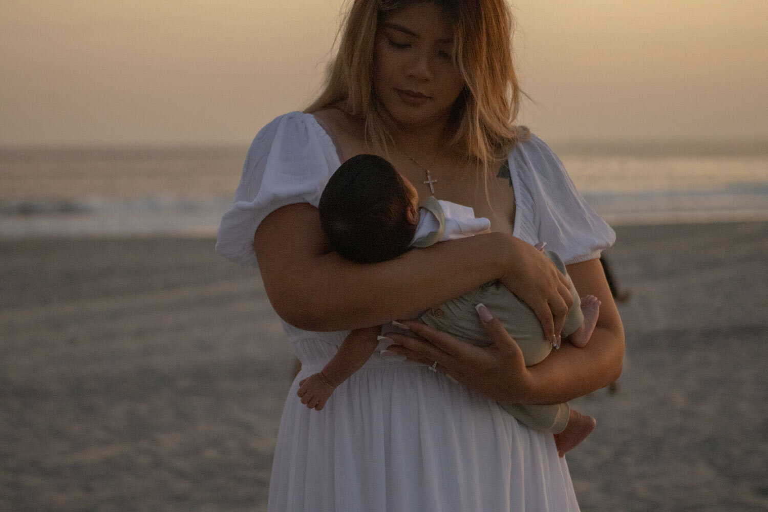 Mother cradling her baby at sunset on the beach, photographed by a San Diego family photographer