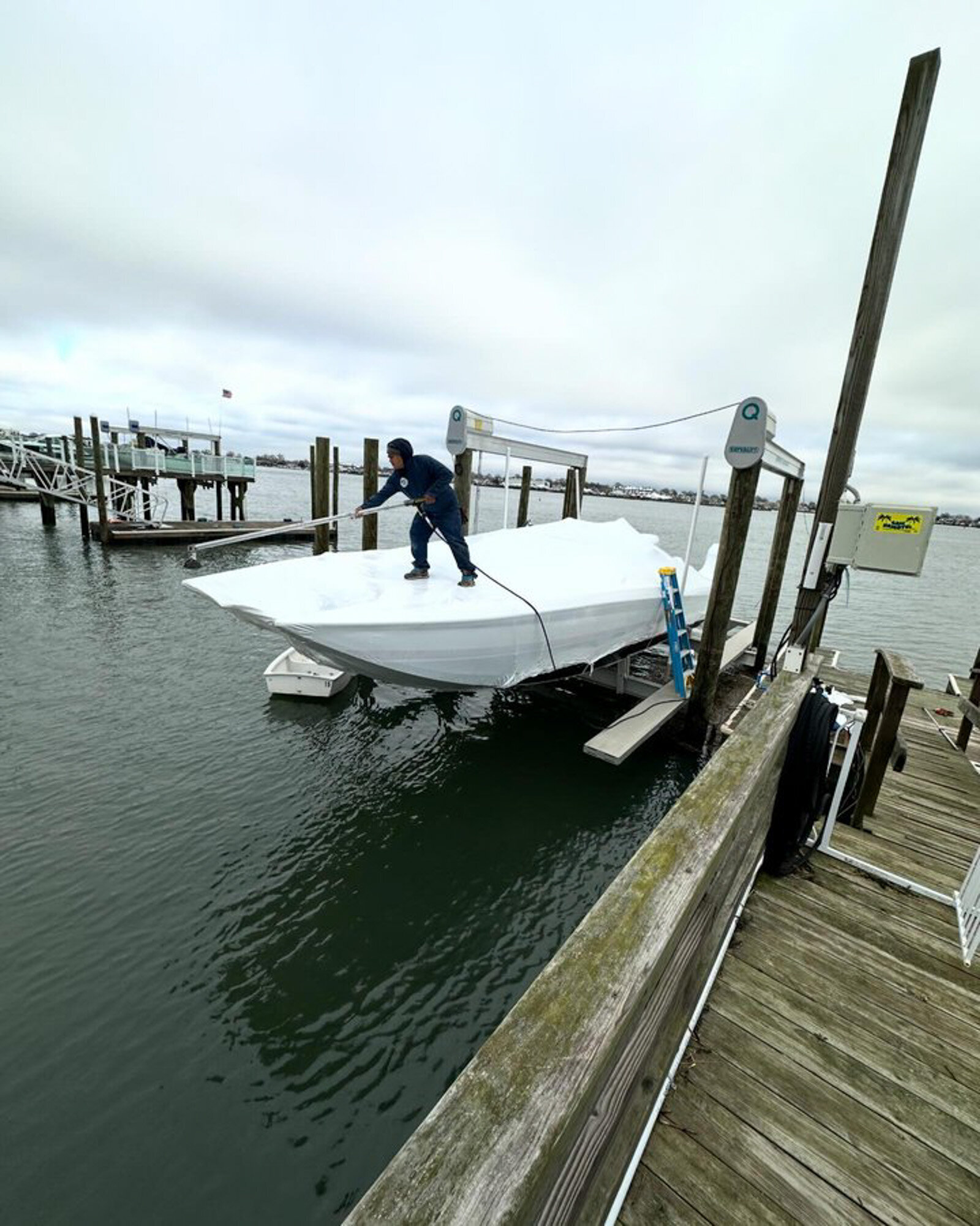 Worker preparing to shrink-wrap a boat at a dock