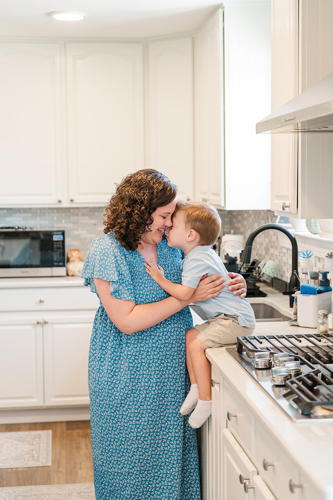 Mother snuggling with her son, who is sitting on the kitchen counter by Baltimore photographer