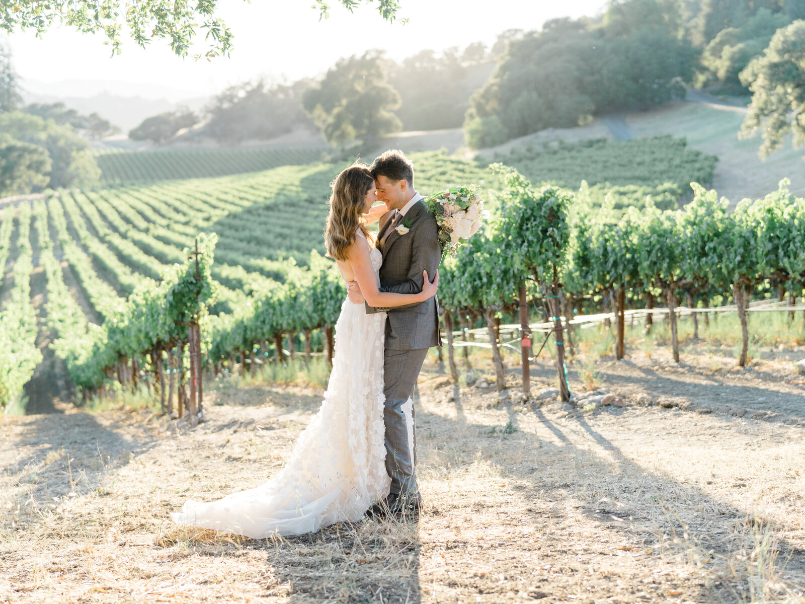 bride and groom holding each other close in a vineyard