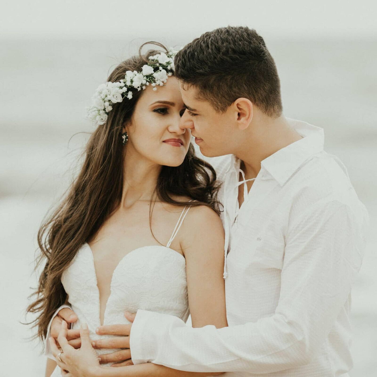 Bride and groom facing each other at the seaside