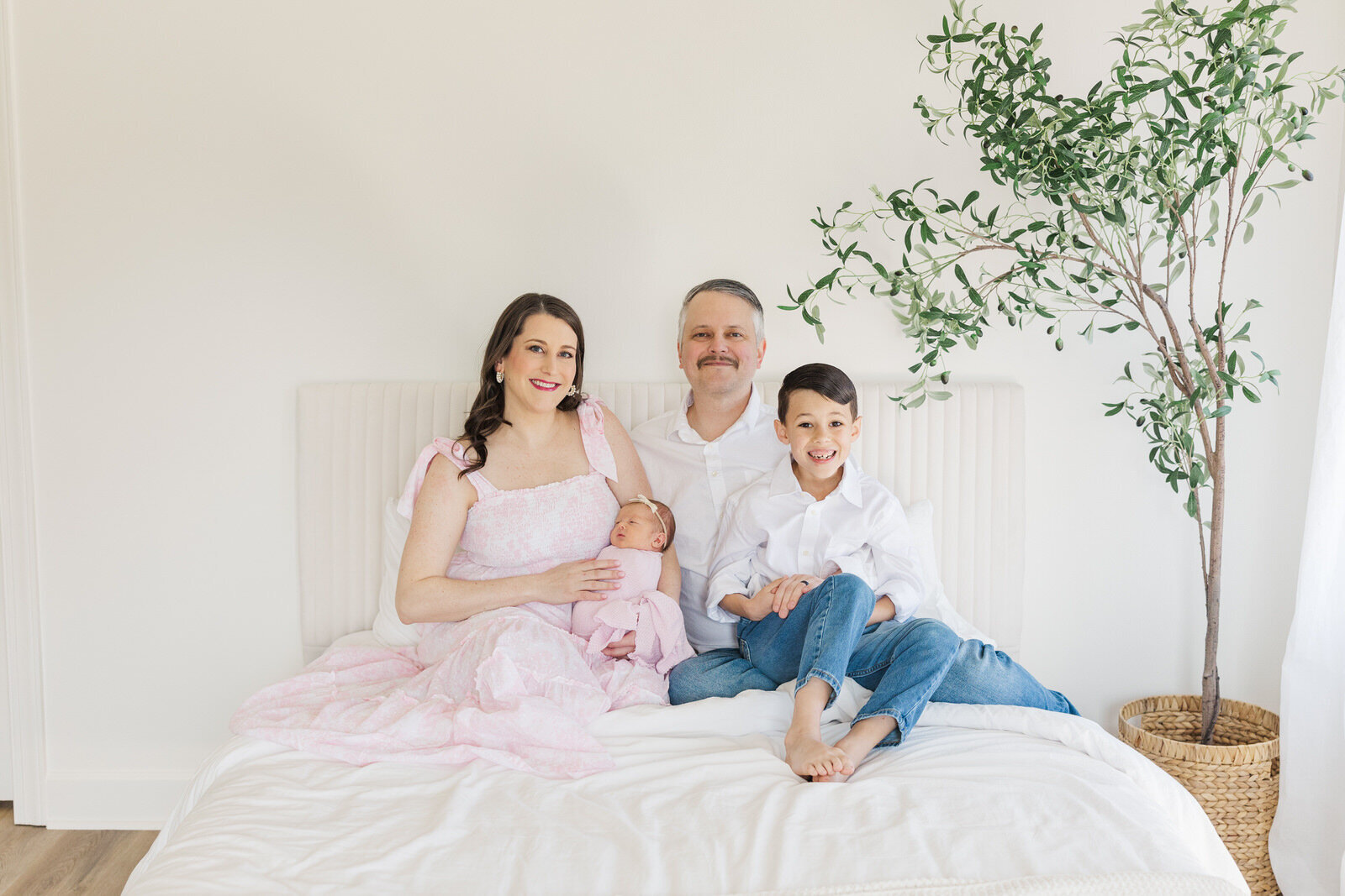 Family of 4 smiles at camera during lifestyle newborn session