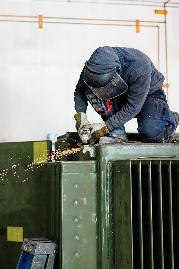 Man welds a green transformer.