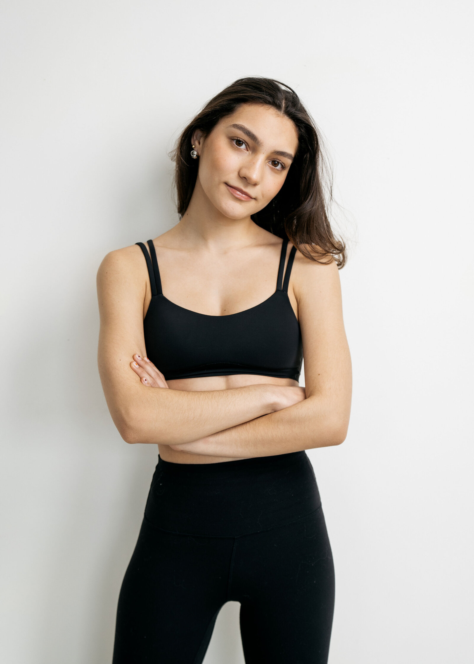 A member in black activewear standing with arms folded